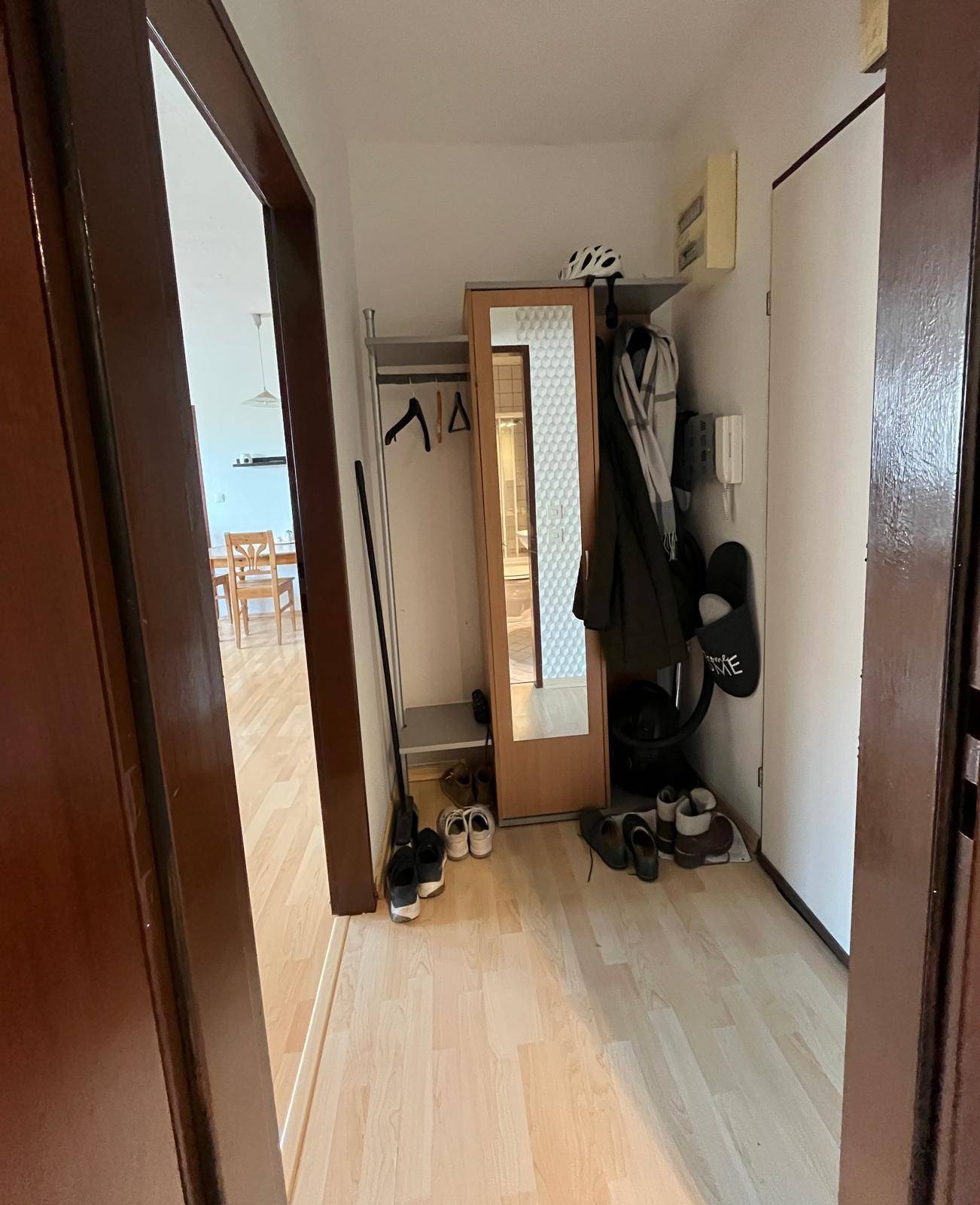 Heller Flur mit Laminatboden, Garderobe und Spiegel, der zu weiteren Räumen führt.