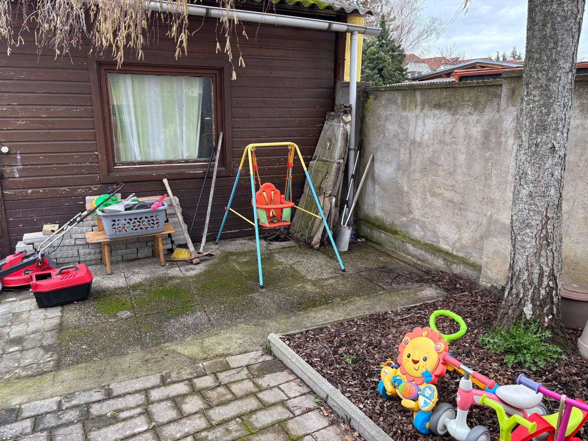Hinterhof mit Gartenhaus, Kinderschaukel und Spielzeug, ideal für Familien.