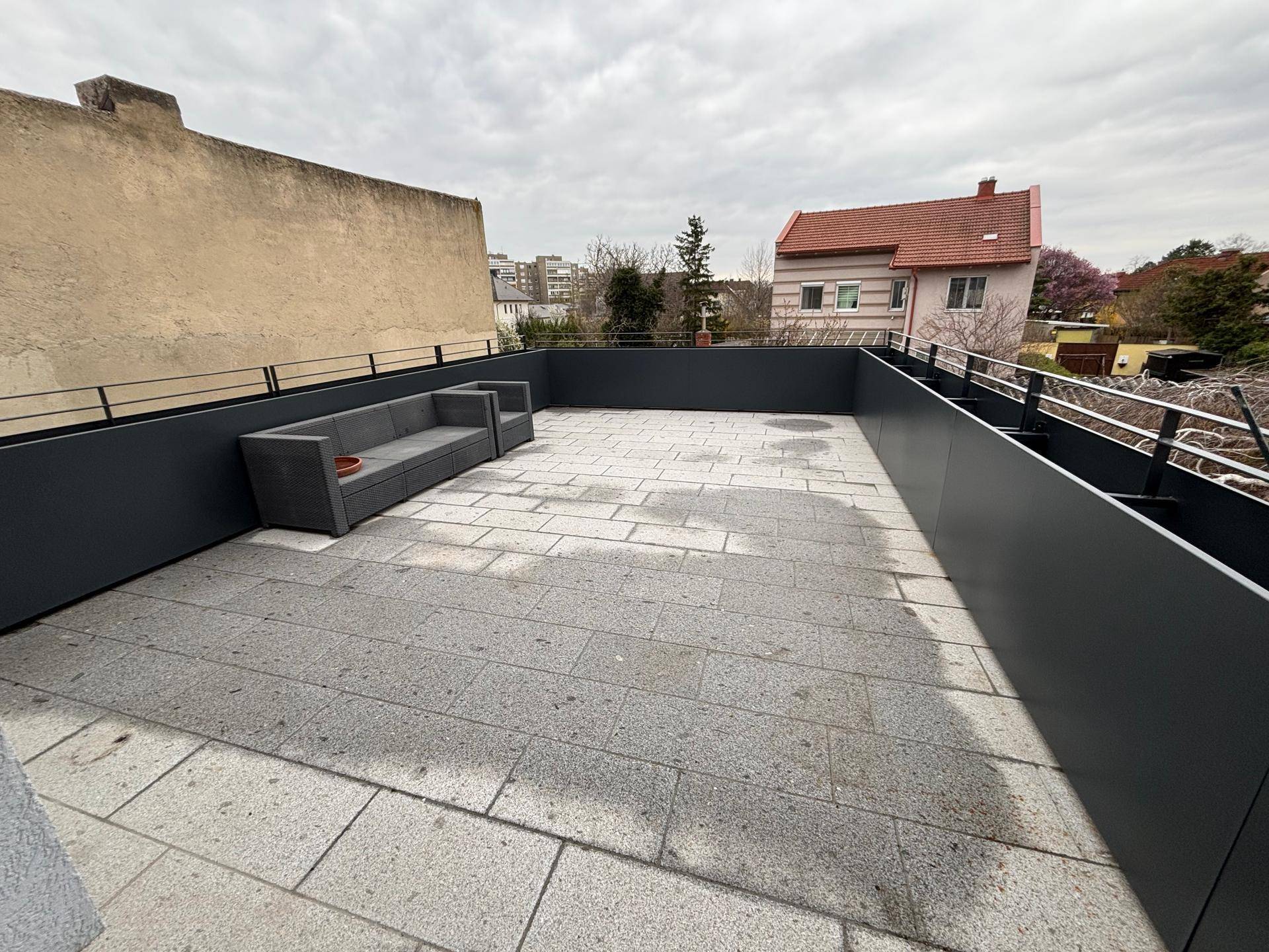 Geräumige Dachterrasse mit modernen Outdoor-Möbeln und Blick auf die Umgebung.