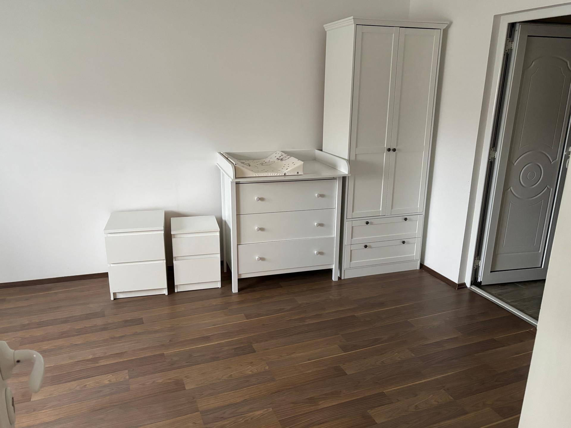 Schlafzimmer mit Laminatboden und weißem Kleiderschrank sowie Kommoden.