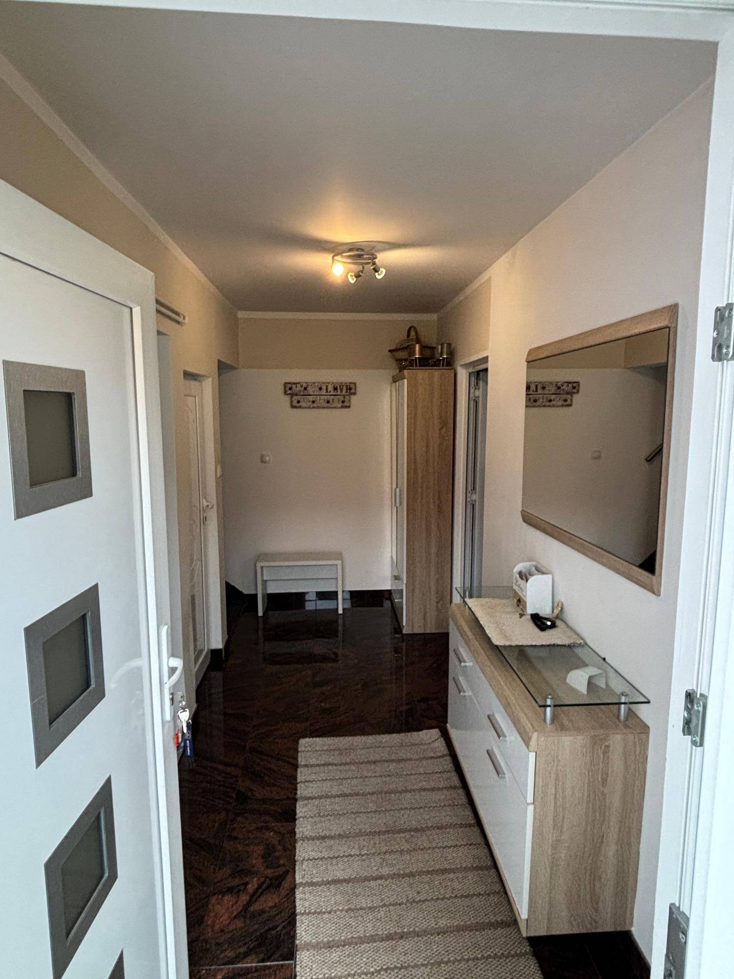 Heller Eingangsbereich mit dunklem Fliesenboden, Garderobe und Spiegel.