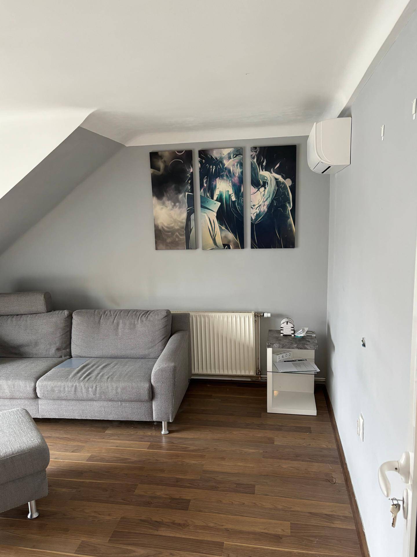 Gemütlicher Wohnbereich im Dachgeschoss mit Schrägdach, Sofa und Laminatboden.