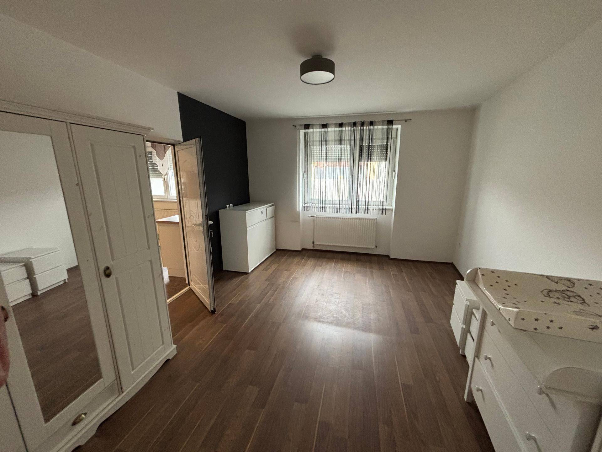 Schlafzimmer mit Laminatboden und weißer Einrichtung, bereit zur individuellen Gestaltung.