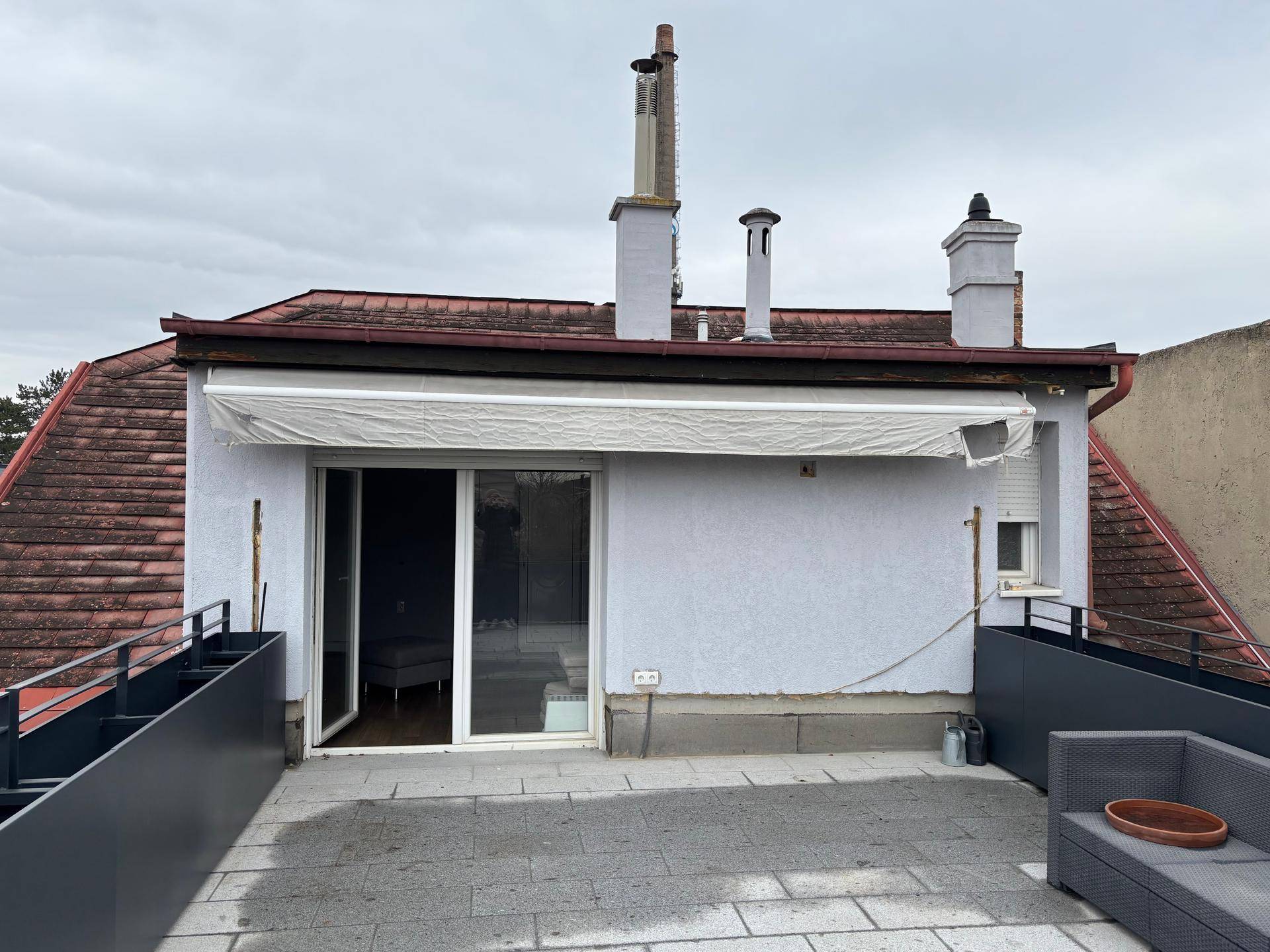 Ansicht des Hauses von der Dachterrasse mit Markise und Schornsteinen.