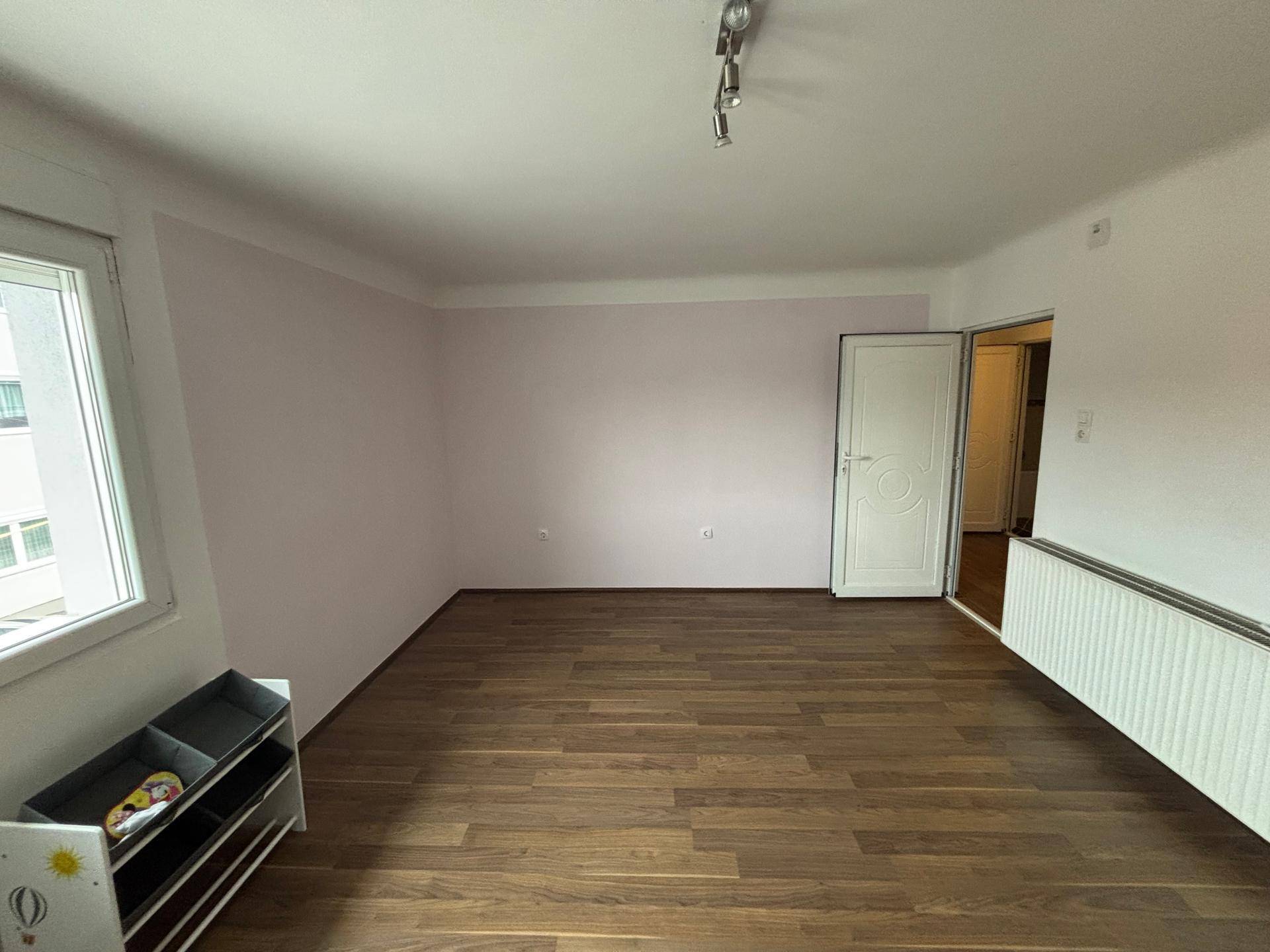 Geräumiges Schlafzimmer im Dachgeschoss mit Laminatboden und hellen Wänden.