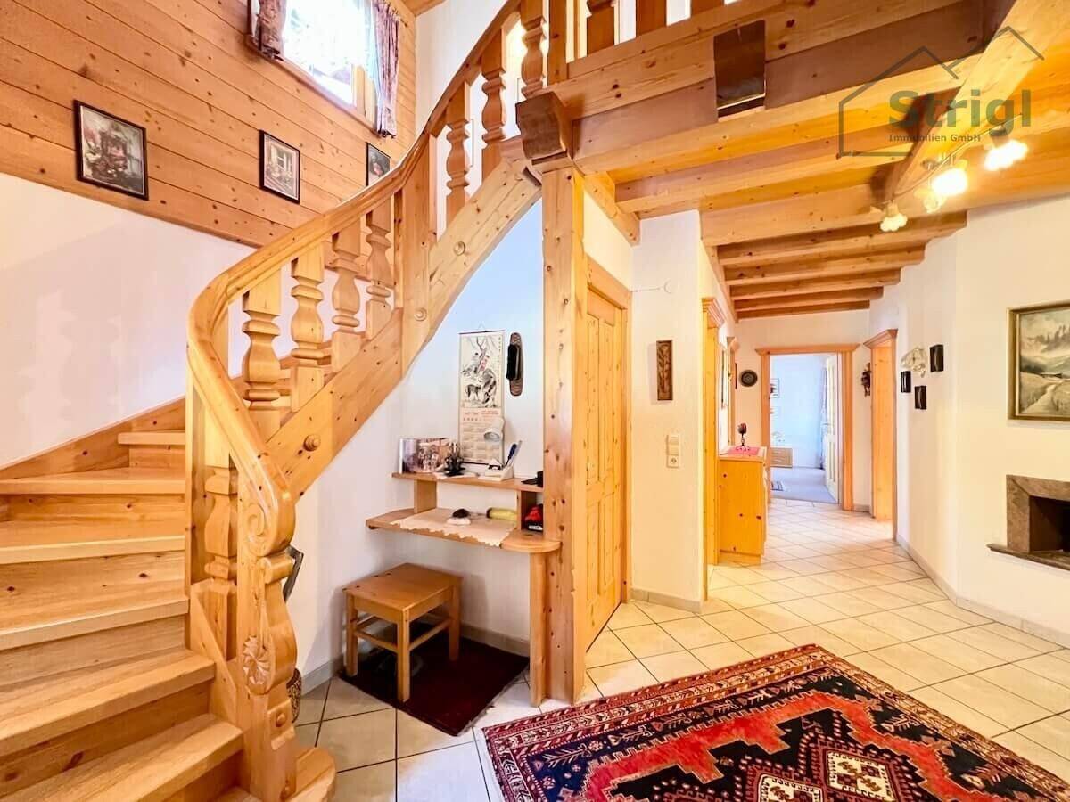 Eingangsbereich mit rustikaler Holztreppe, die in die oberen Stockwerke führt, und Fliesenboden.