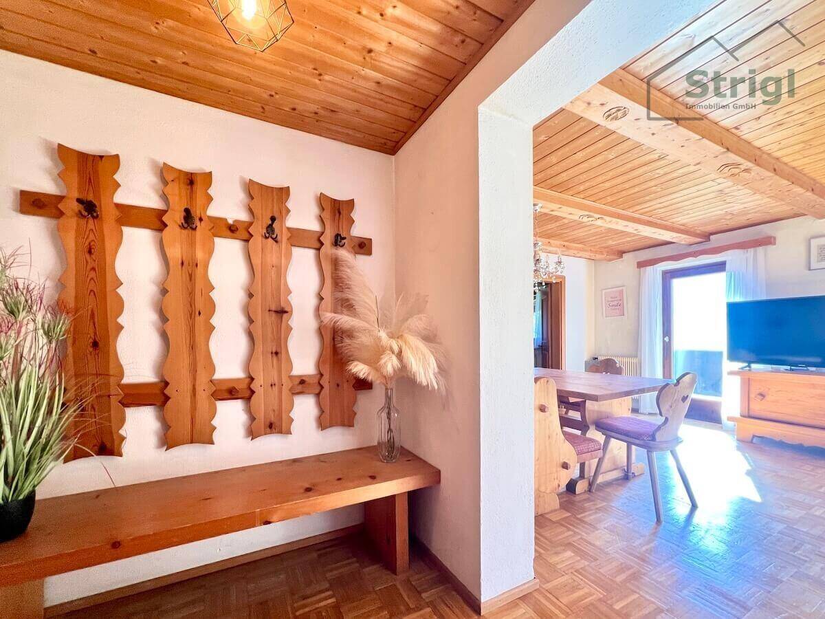 Gemütlicher Eingangsbereich mit rustikaler Holzgarderobe, der in einen hellen Essbereich übergeht.