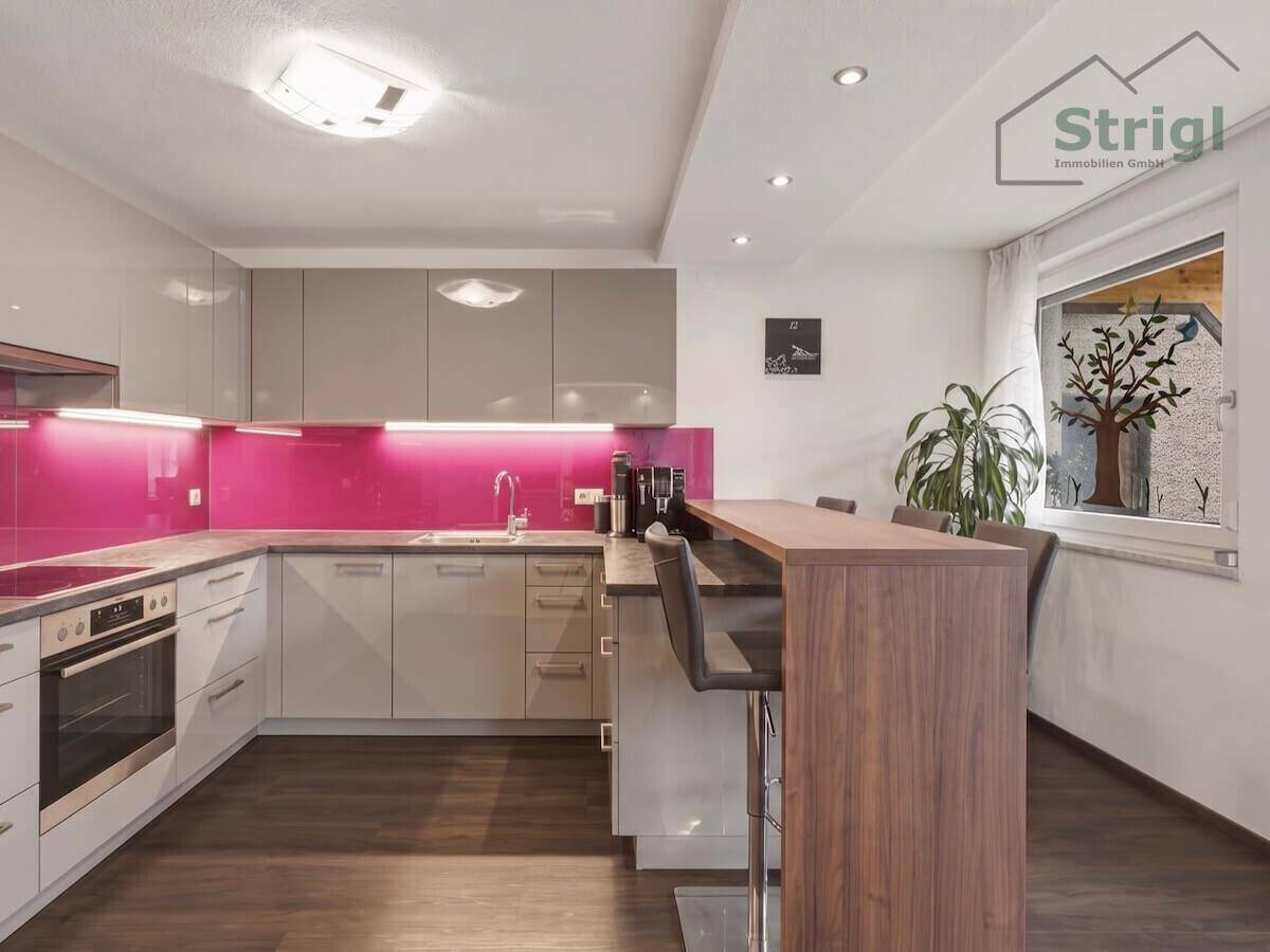 Moderne Küche mit grauen Schränken, pinker Rückwand und praktischer Frühstücksbar.
