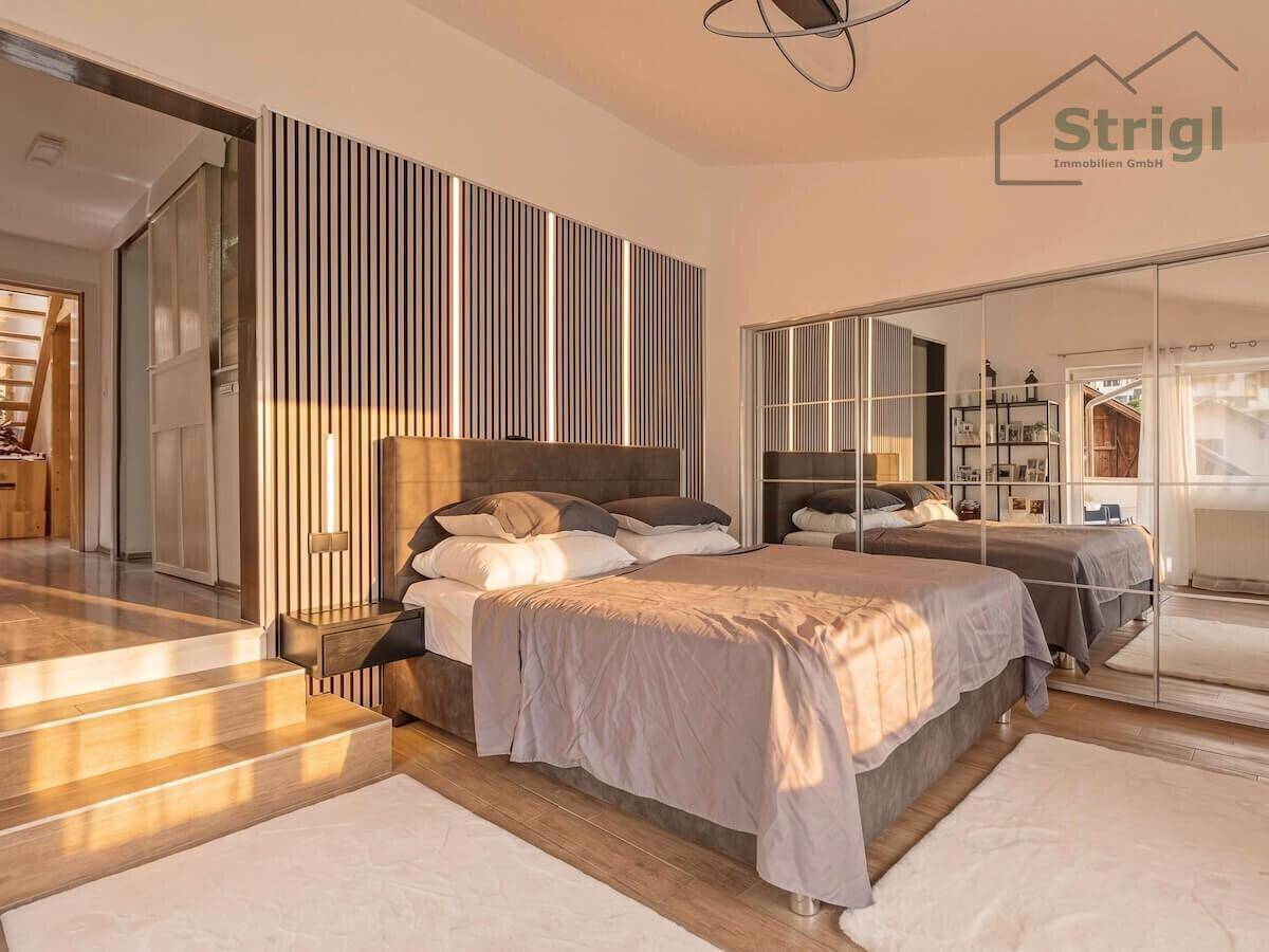 Modernes Schlafzimmer mit großem Bett, Spiegelschränken und dekorativer Wandverkleidung mit Beleuchtung.