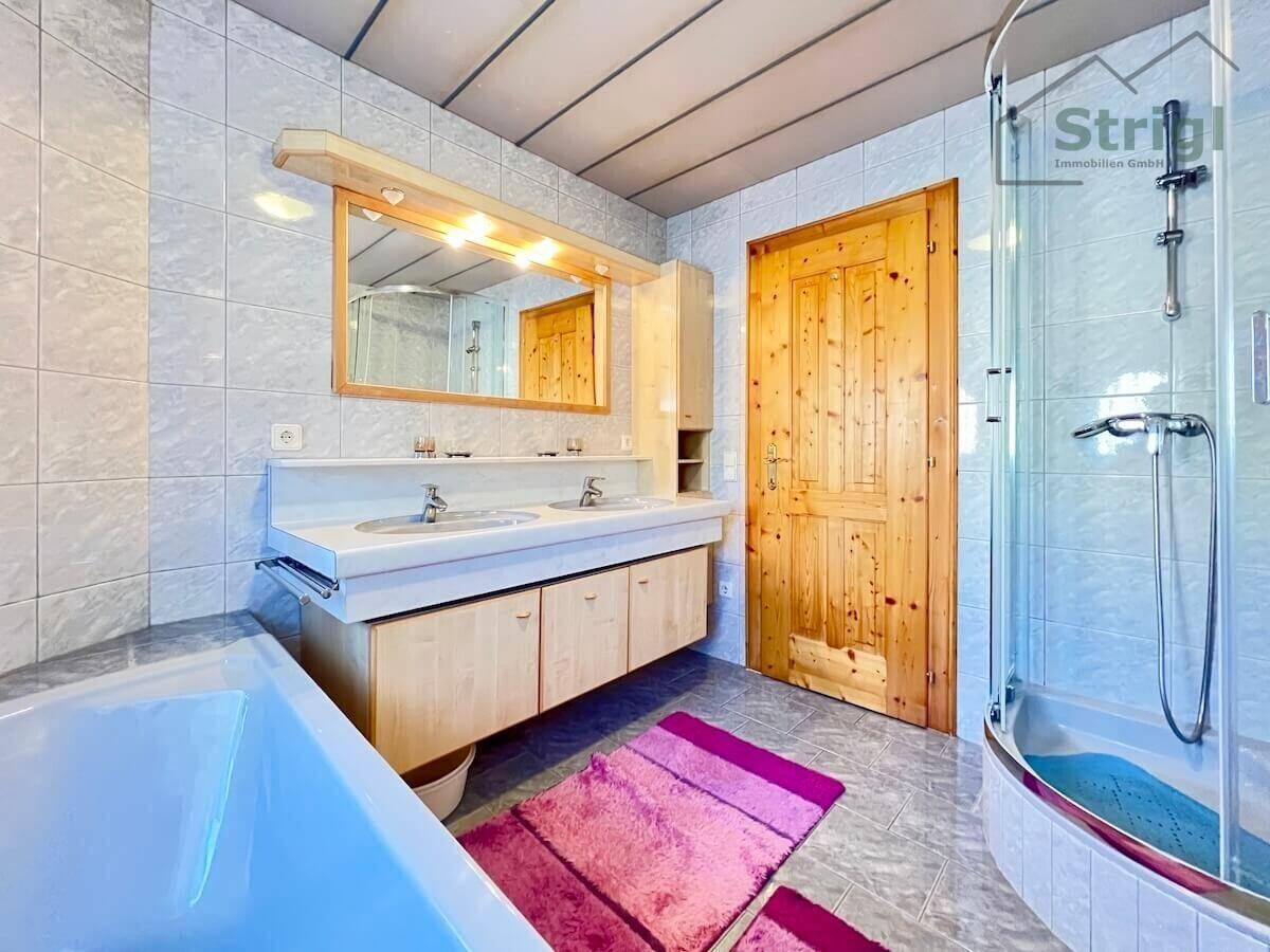 Funktionales Badezimmer mit Doppelwaschbecken, Badewanne, Dusche und hellen Fliesen.
