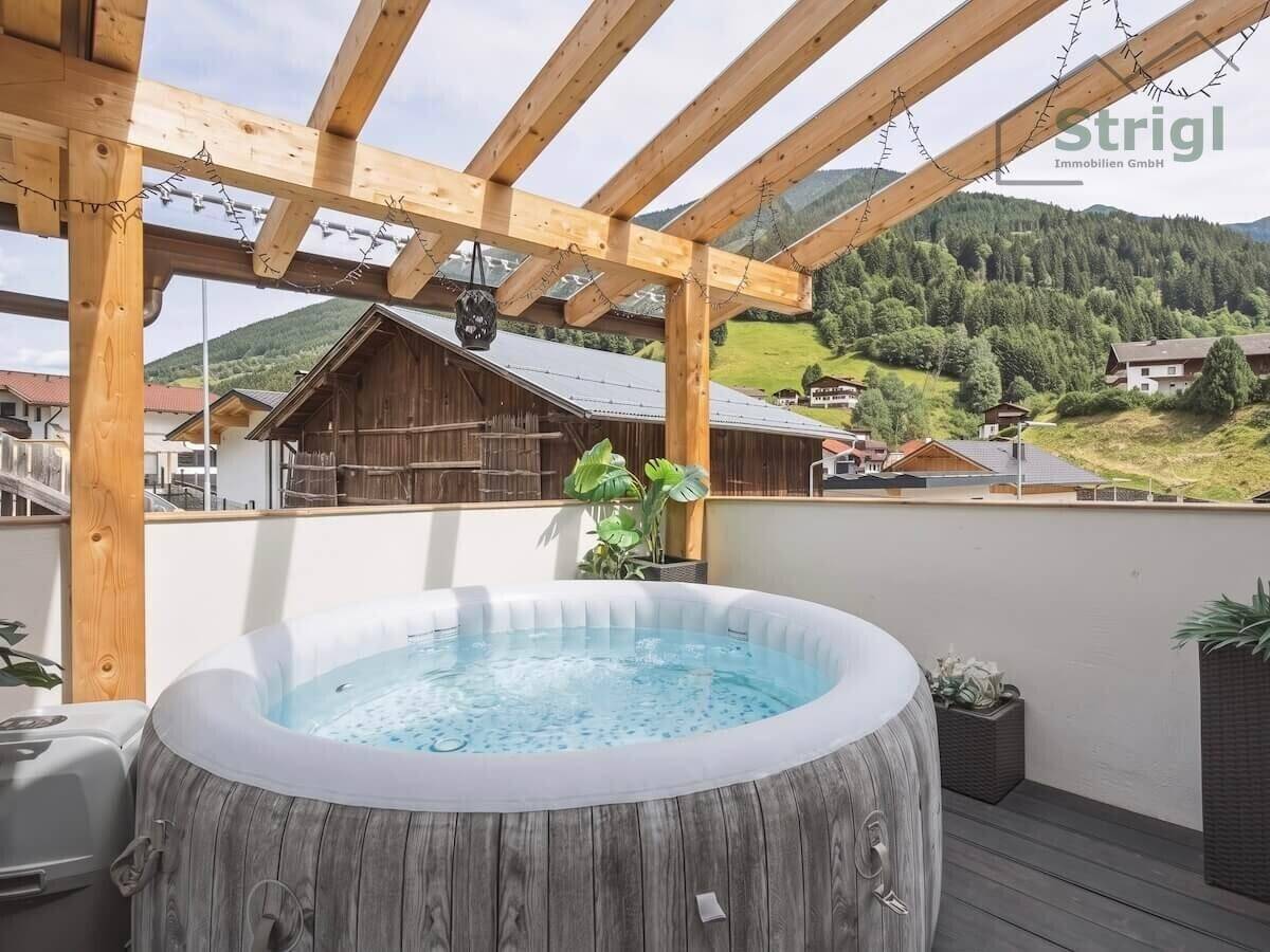 Entspannende Terrasse mit aufblasbarem Whirlpool unter einer Holzpergola und Bergblick.