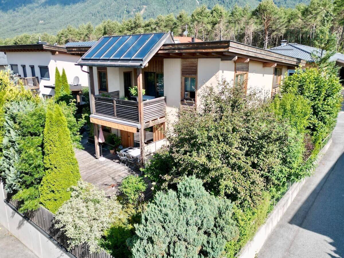 Ansicht des modernen Hauses mit Garten, Solaranlage und umliegender Nachbarschaft.