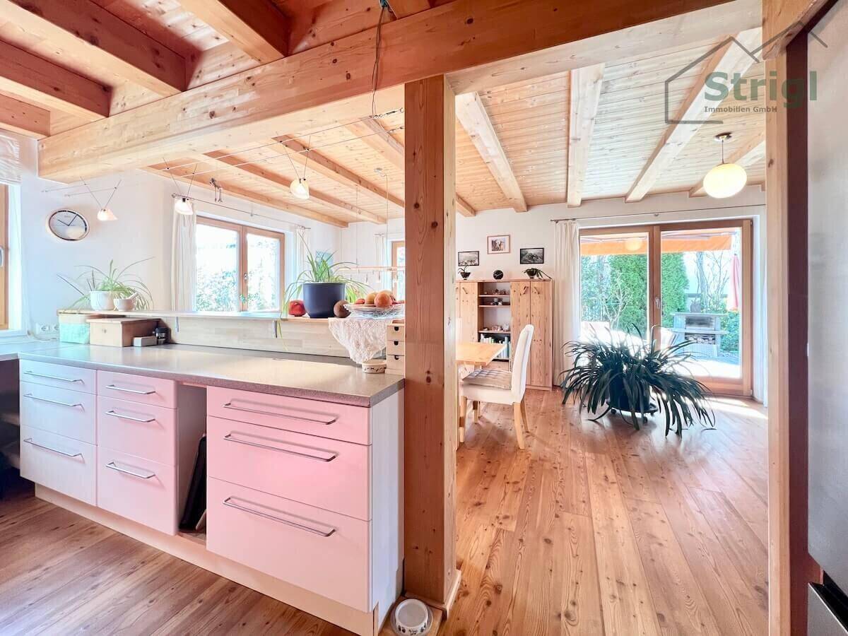 Helle Küche mit modernen Schränken und Blick auf den Essbereich sowie den Garten.