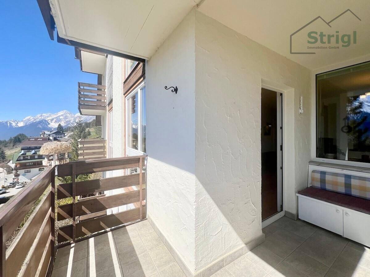 Sonniger Balkon mit Holzbalkonbrüstung und Fliesenboden, bietet einen schönen Bergblick.