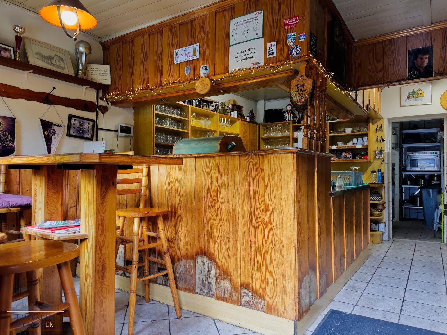 Traditionelle Bar mit Holzvertäfelung, Theke und zahlreichen Gläsern, einladend für Gäste.