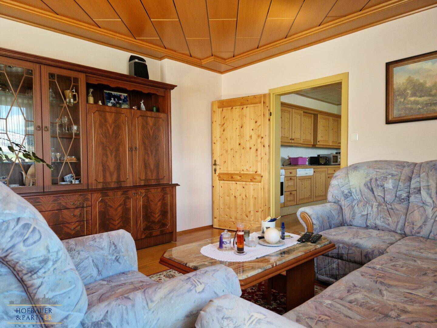 Wohnzimmer mit traditionellen Holzmöbeln, bequemen Sofas und Zugang zur Küche.
