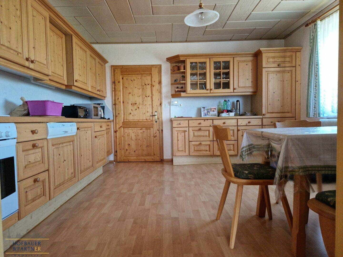 Funktionale Küche mit Holzfronten, Essbereich und Laminatboden.