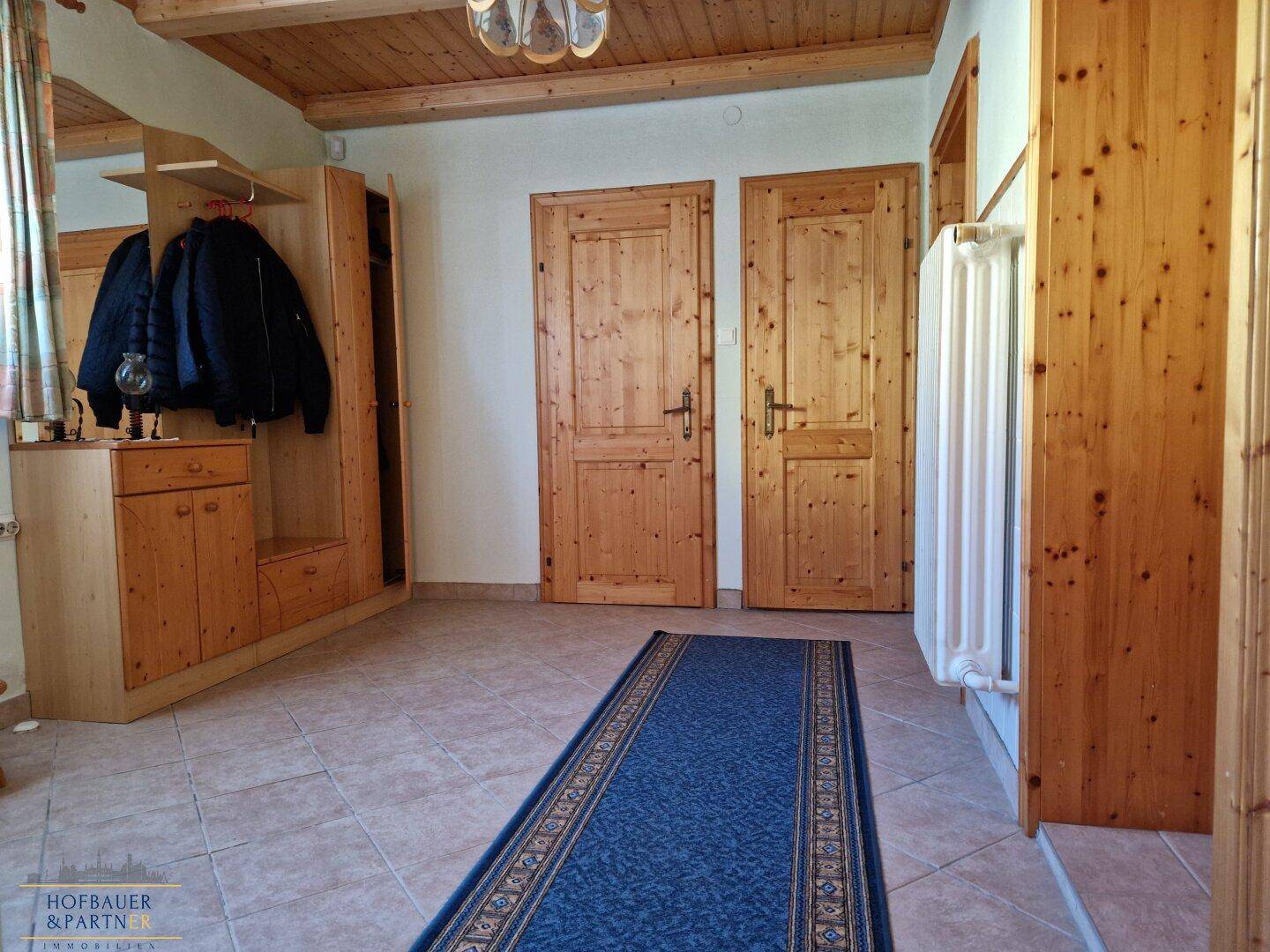 Geräumiger Flur mit Garderobe, Holzdecke und Fliesenboden.