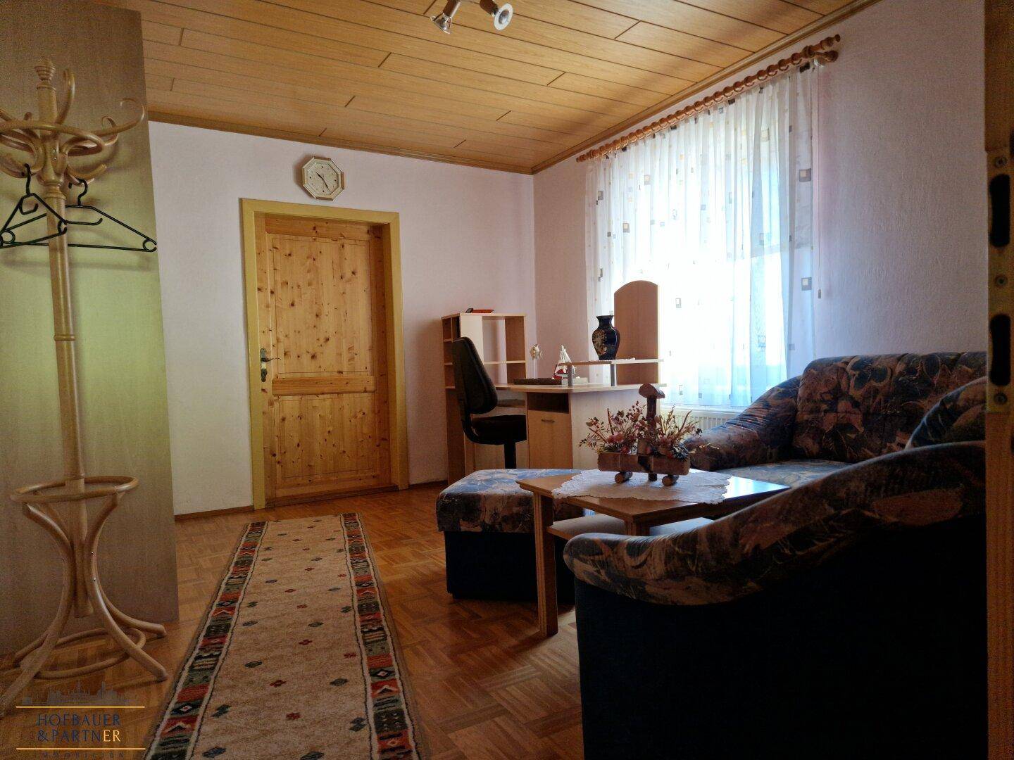 Gemütlicher Wohnbereich mit Sofa, Schreibtisch und Holzdecke.