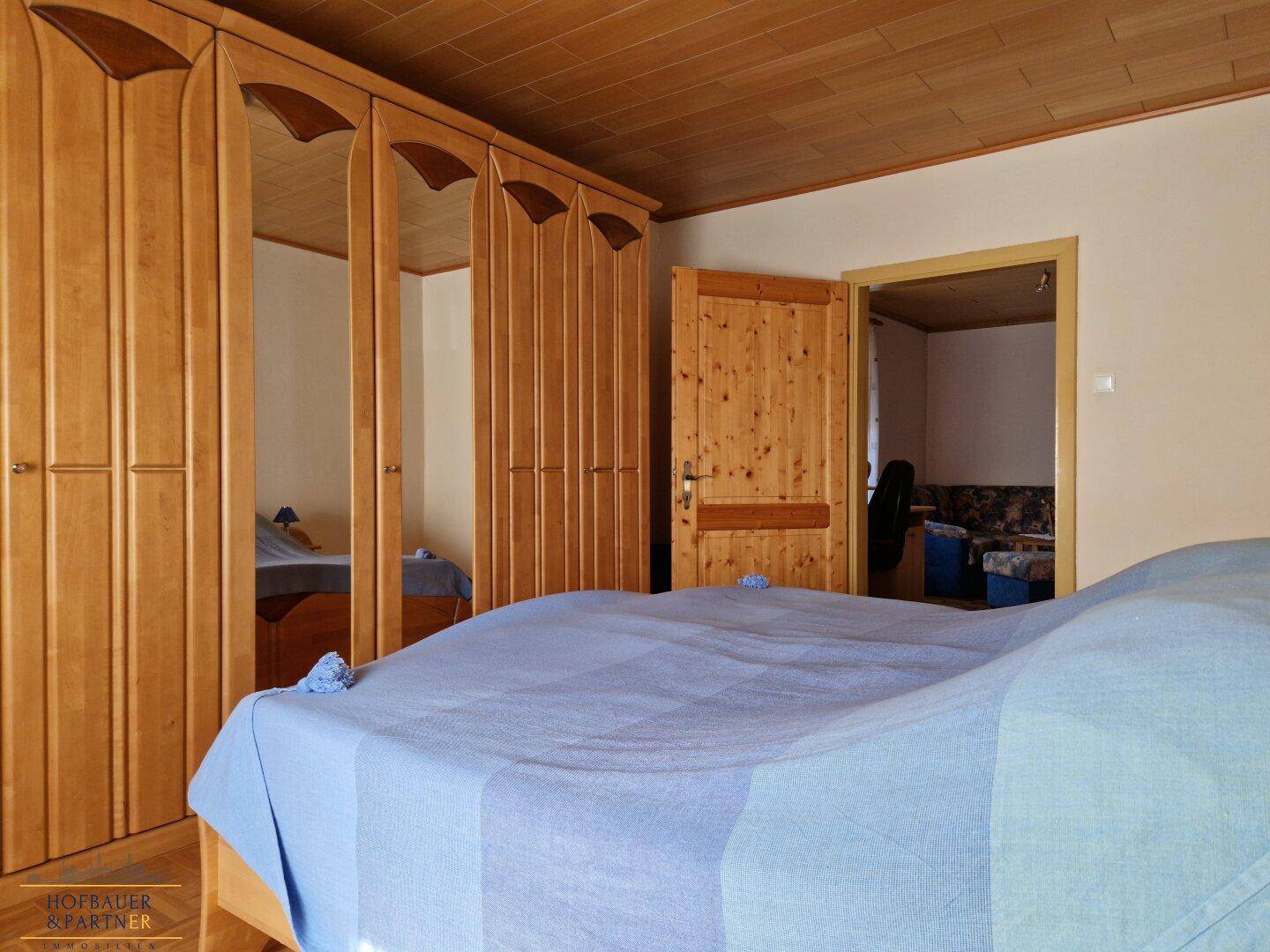 Schlafzimmer mit Holzdecke, Einbauschränken und Doppelbett.