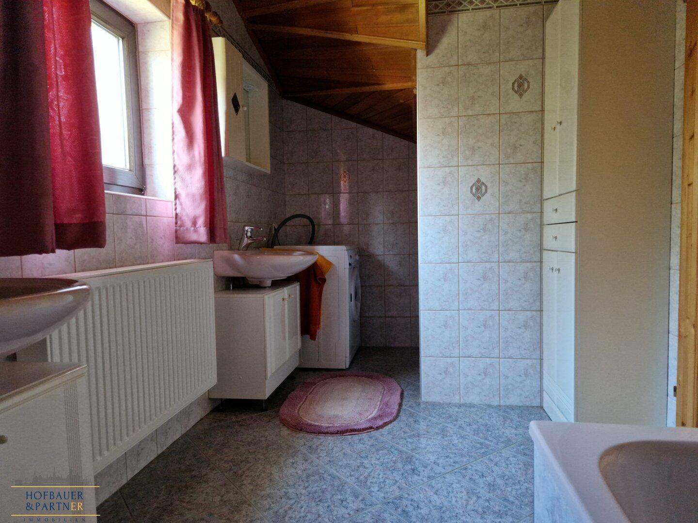Helles Badezimmer mit Waschbecken, Waschmaschine und Dachschräge.