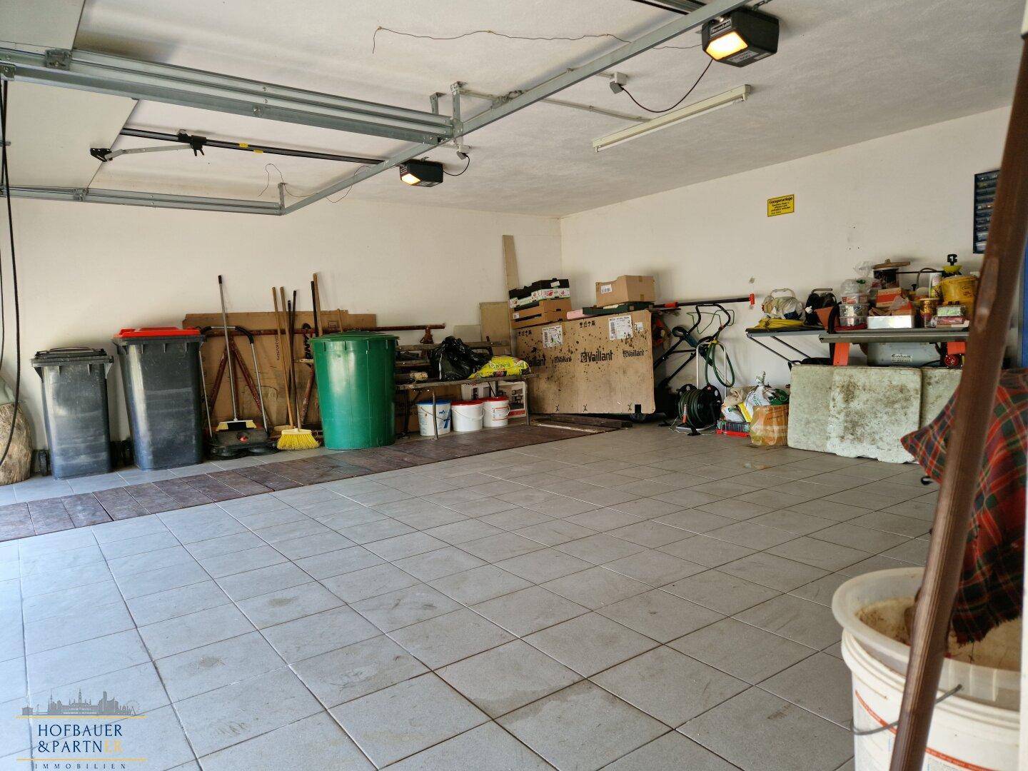 Geräumige Garage mit Fliesenboden, Stauraum und Werkzeugen.