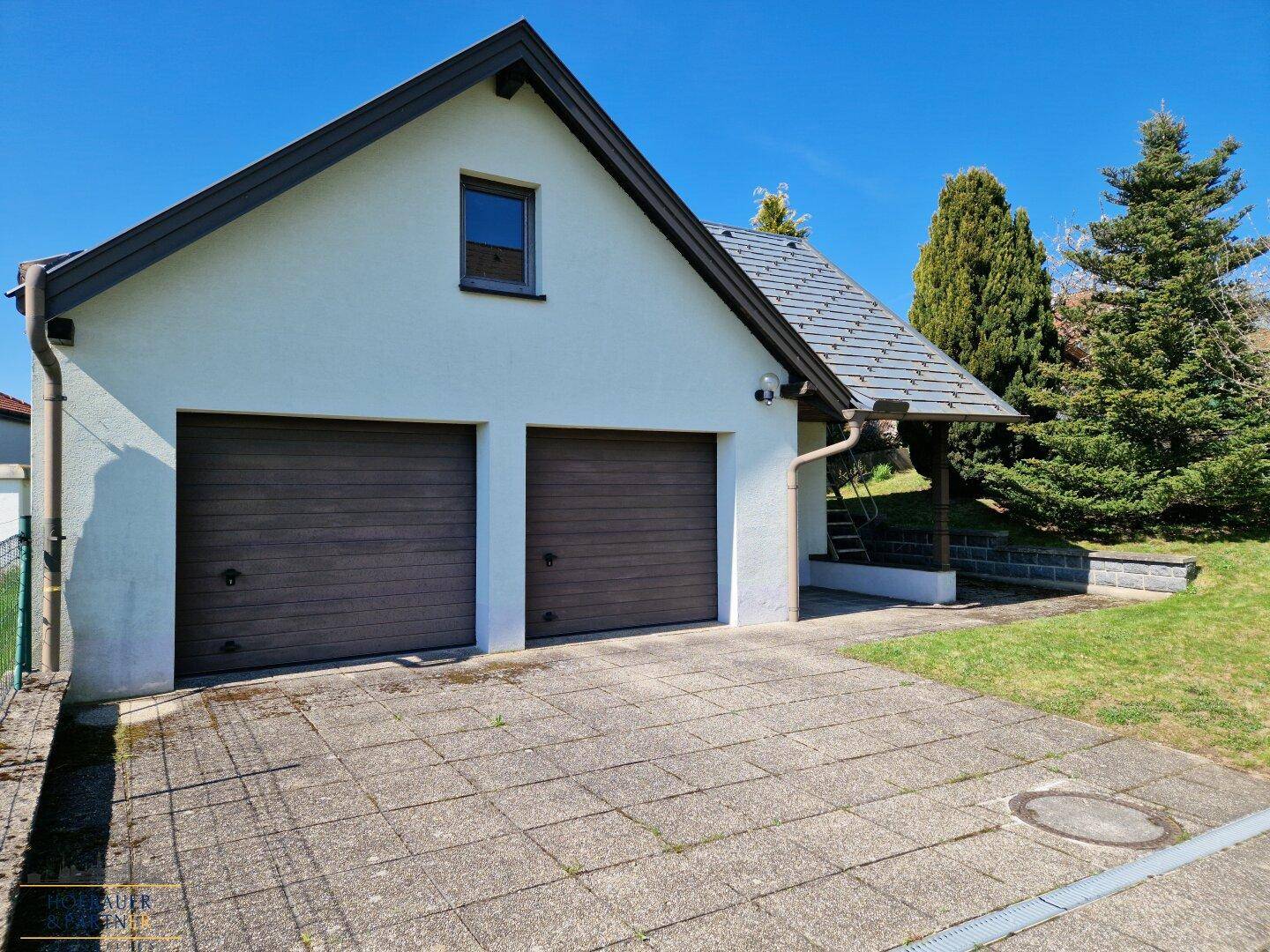 Doppelgarage mit zwei Toren, gepflastertem Vorplatz und Satteldach.