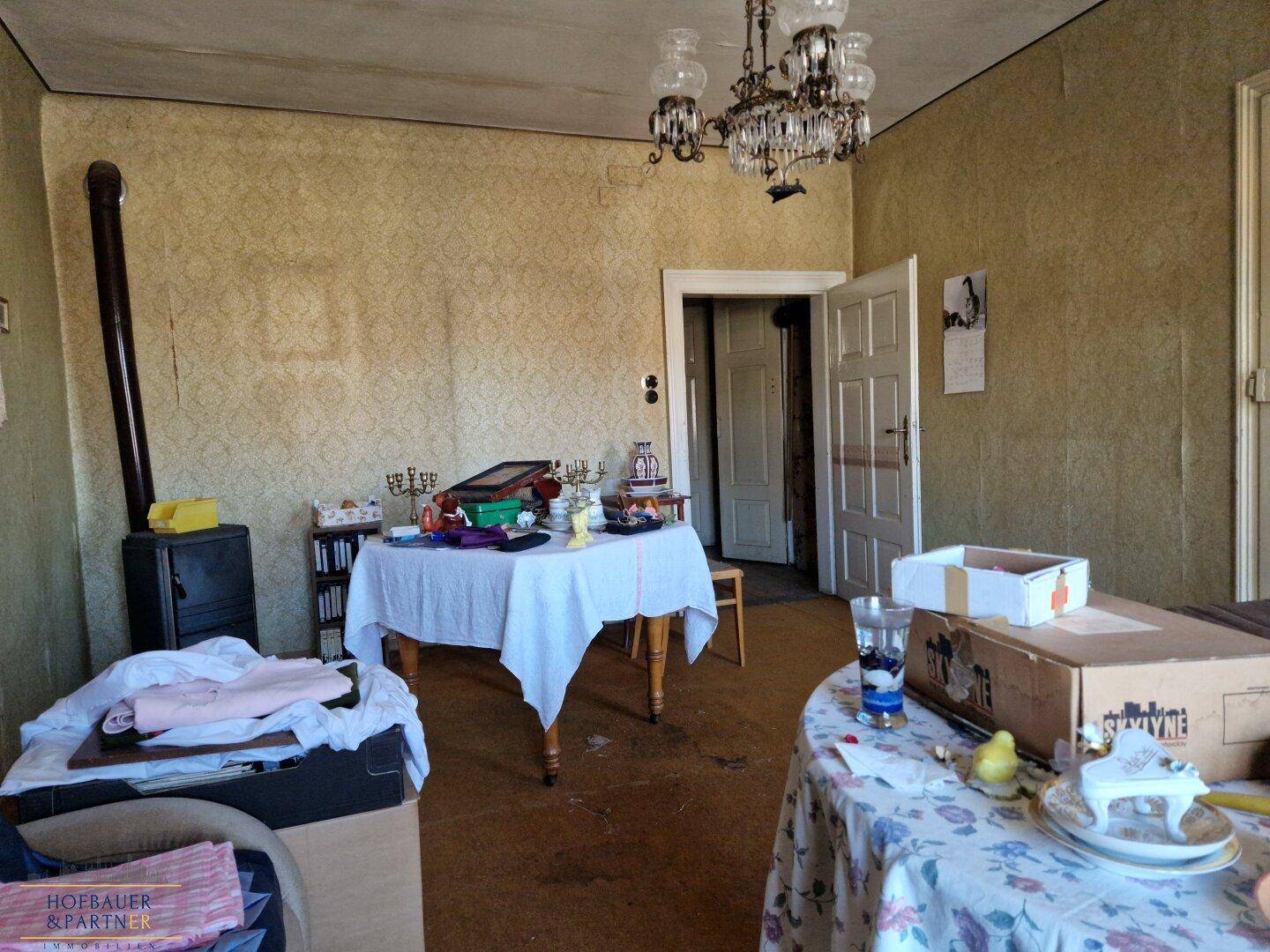 Wohnzimmer mit Kaminofen, Esstischen und Kronleuchter.