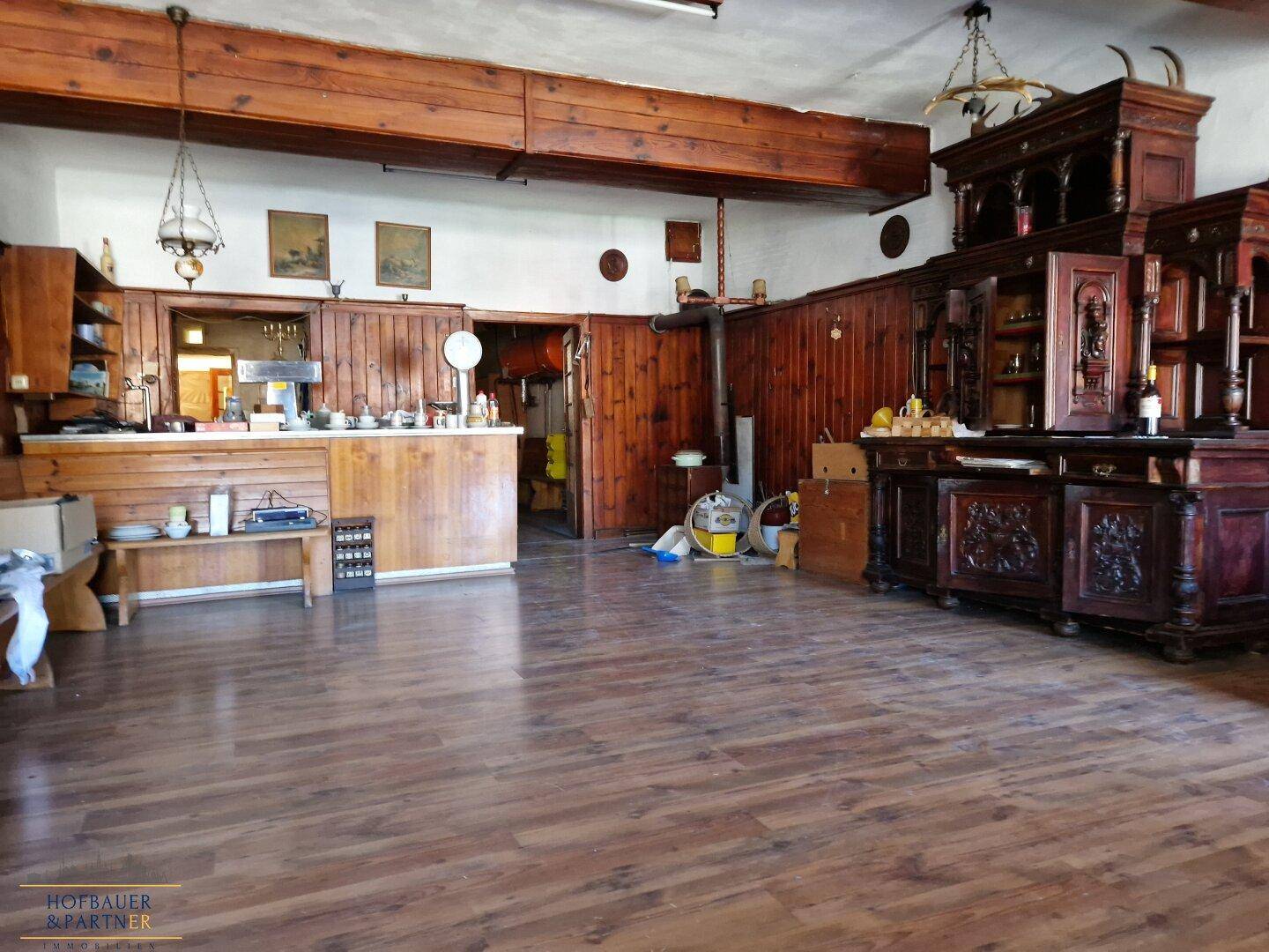 Großer rustikaler Raum mit Holzbalken, Wandvertäfelung und einer Theke.