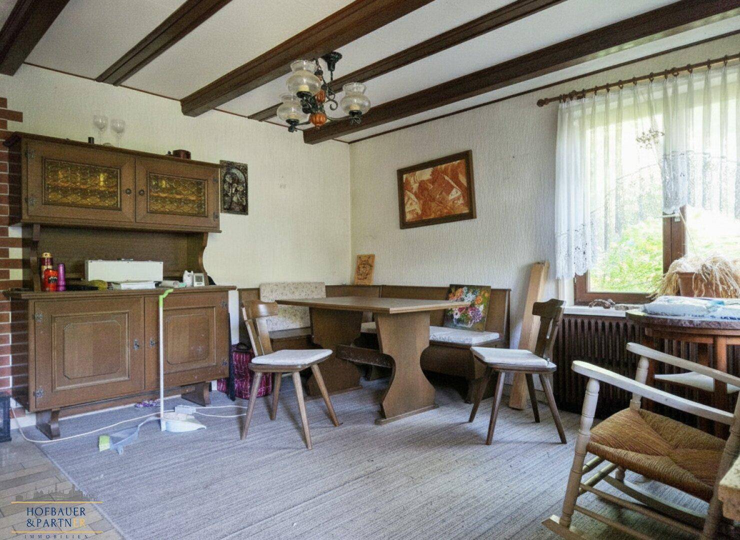 Esszimmer mit Holzbalkendecke, traditionellen Möbeln und Fenster mit Blick nach draußen.
