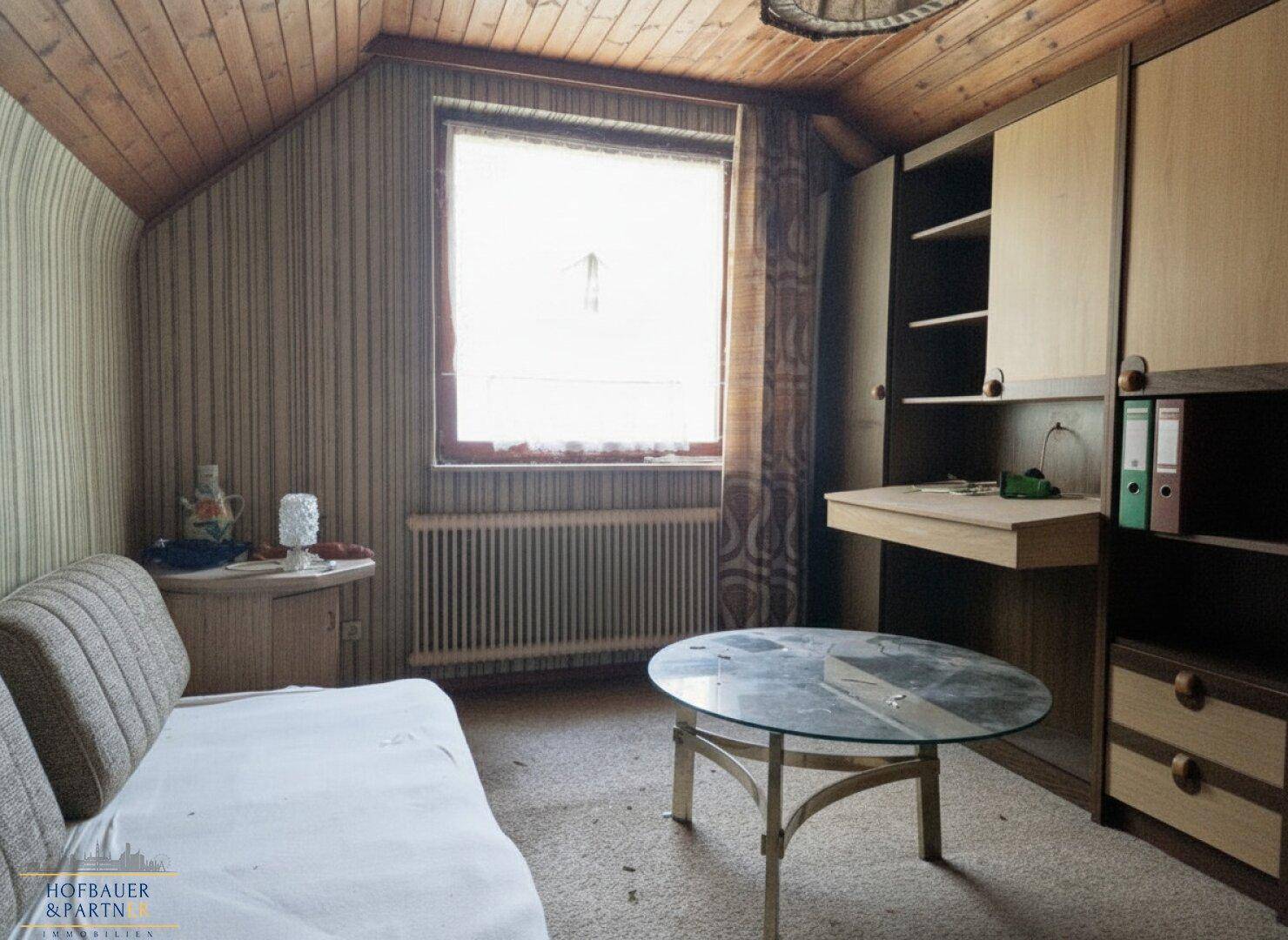 Kleines Arbeitszimmer mit Dachschräge, Holzdecke und integriertem Schreibtischbereich.