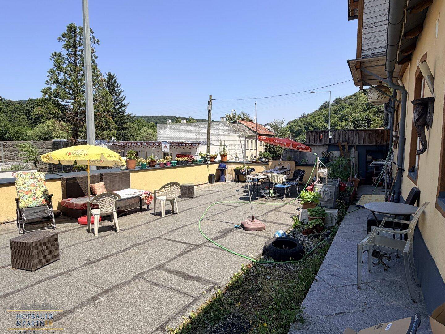 Große gepflasterte Terrasse mit verschiedenen Gartenmöbeln und Sonnenschirmen für entspannte Stunden.