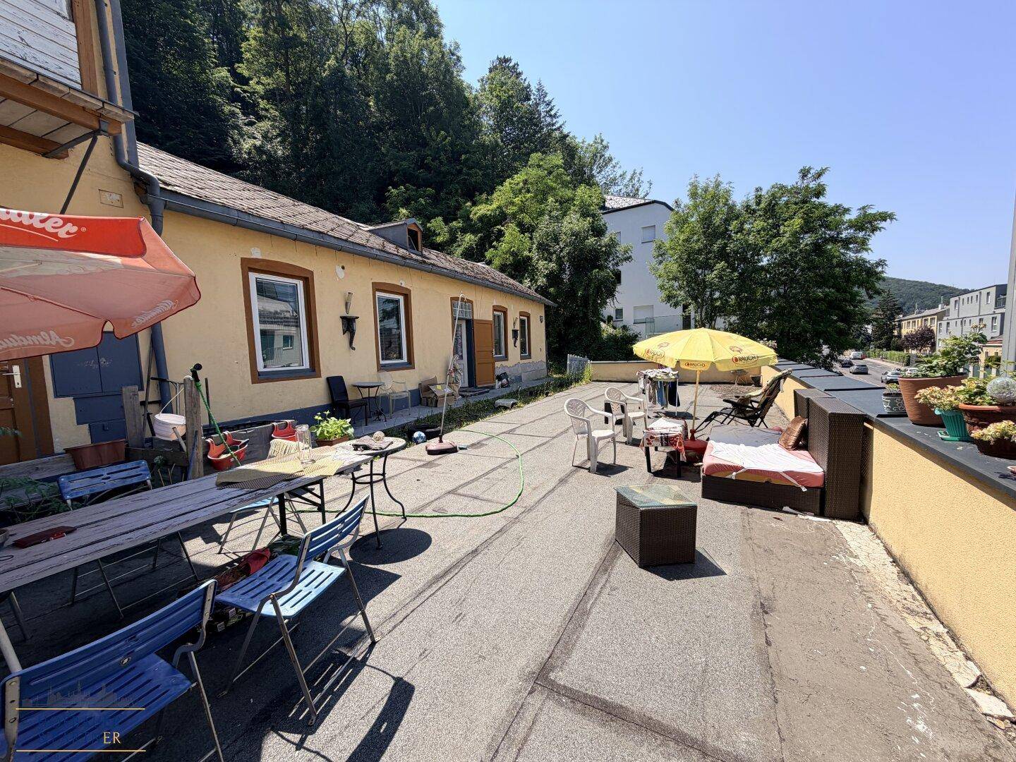 Weitläufige Terrasse mit Sitzgelegenheiten und Blick auf die umliegende grüne Landschaft.