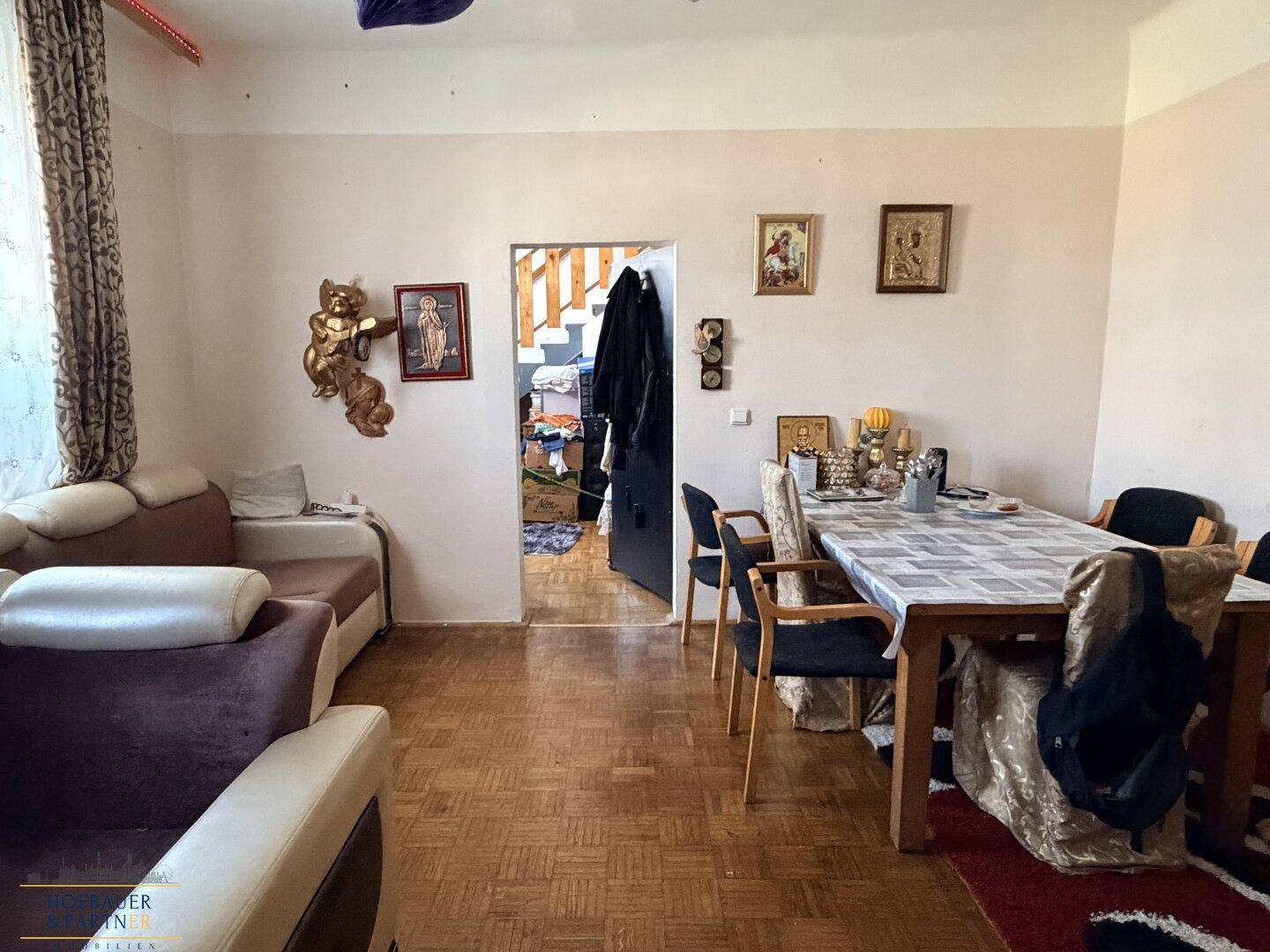 Geräumiger Wohn-Essbereich mit bequemen Sofas, Esstisch und klassischem Parkettboden.
