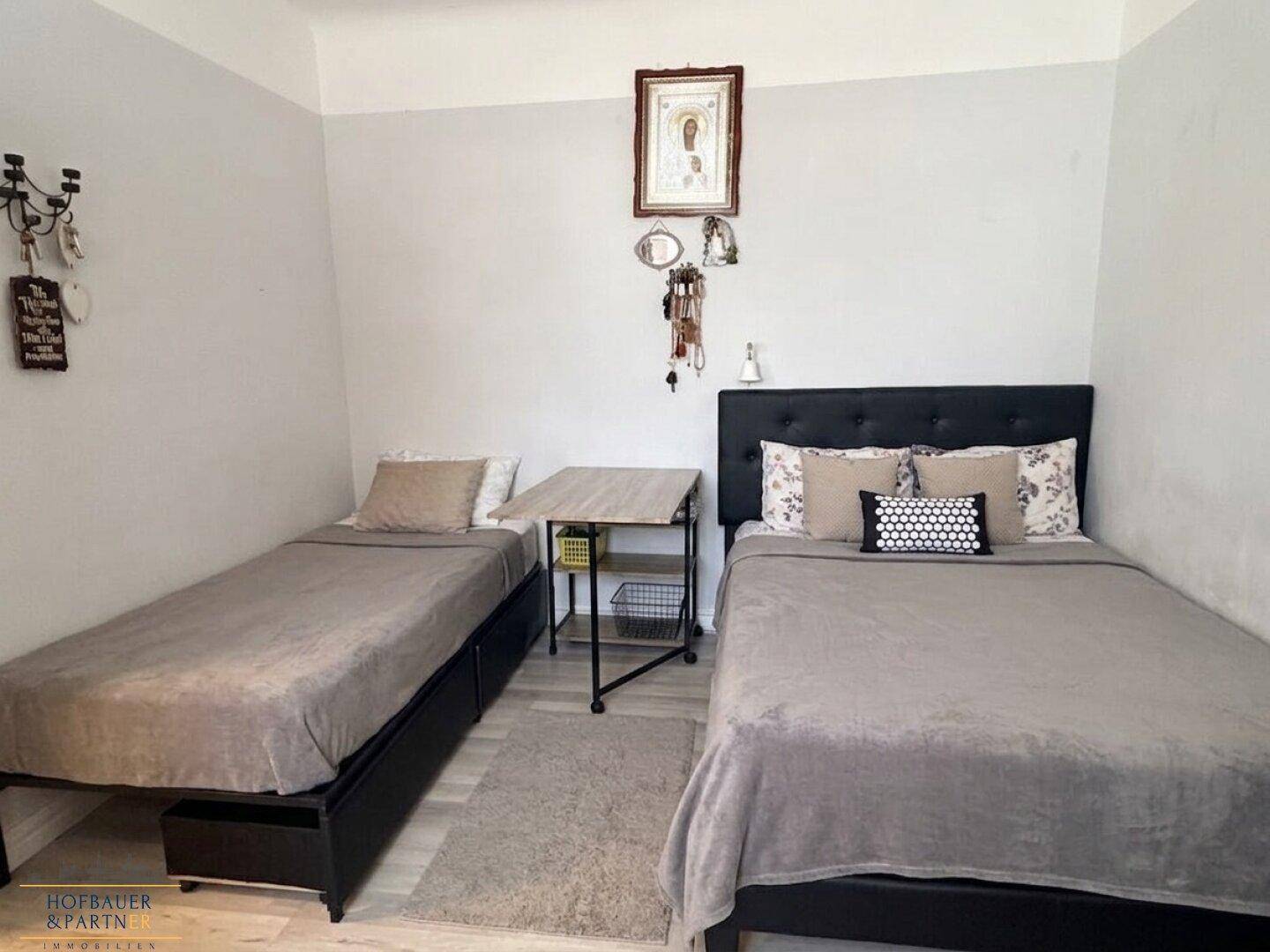 Gemütliches Schlafzimmer mit zwei Einzelbetten, Teppichboden und einfacher Dekoration.