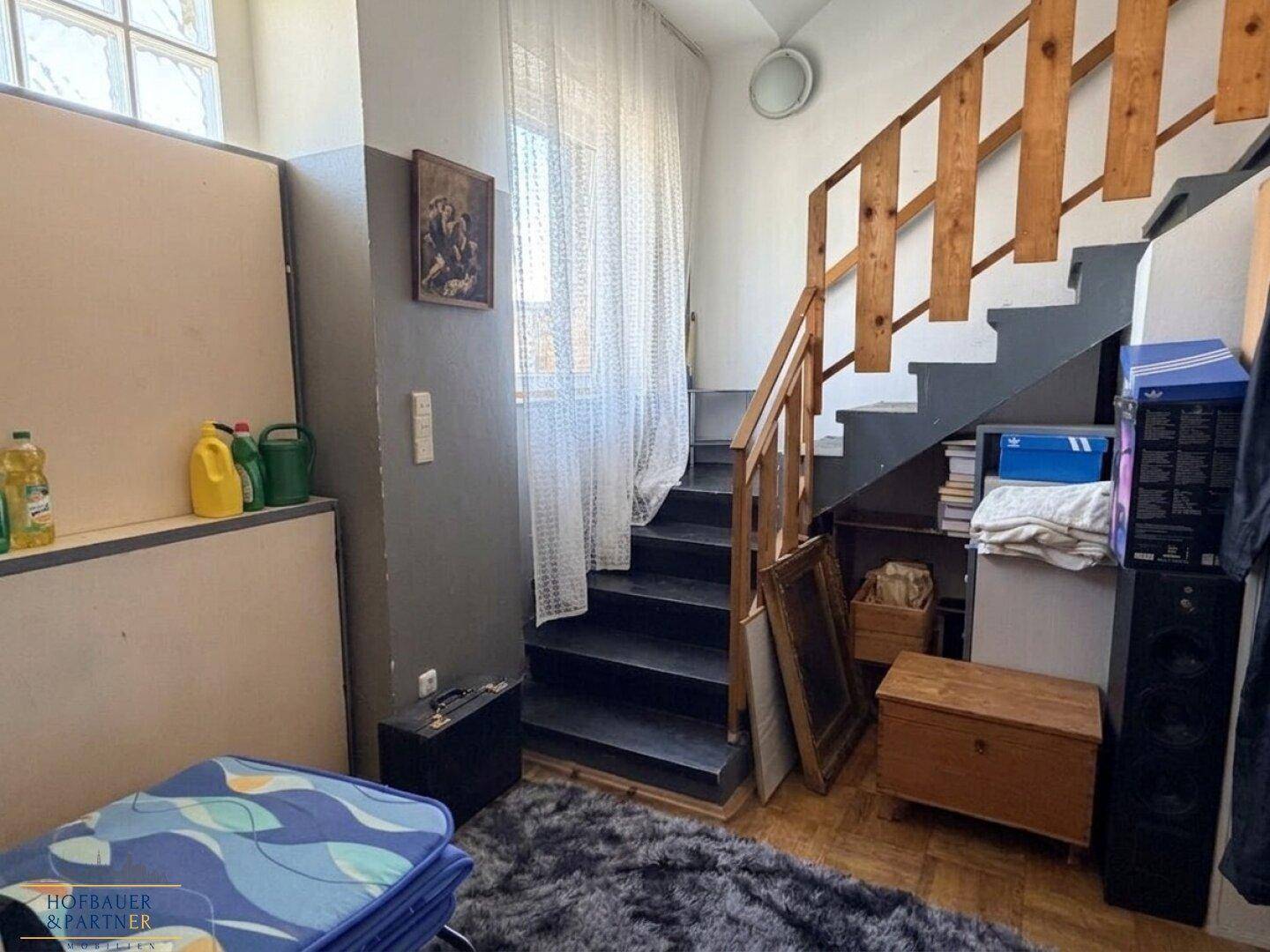 Bereich neben der Treppe mit Teppichboden, Stauraum und natürlichem Lichteinfall.
