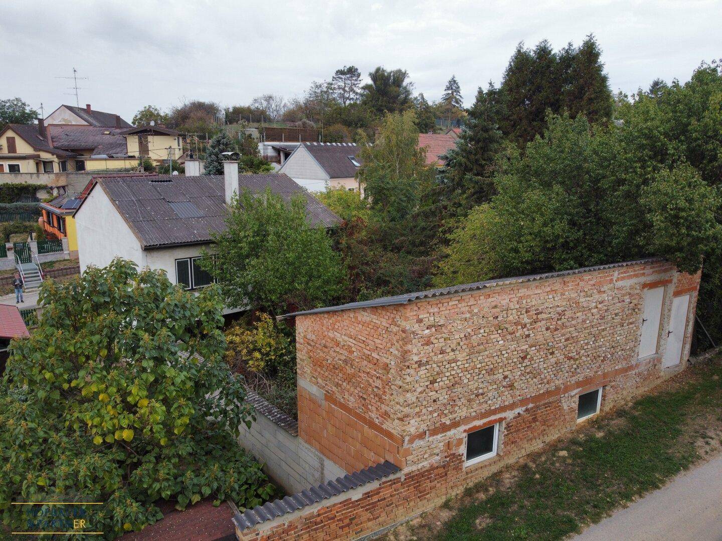 Überblick über das Anwesen mit Haupthaus und Nebengebäude inmitten von Grün.