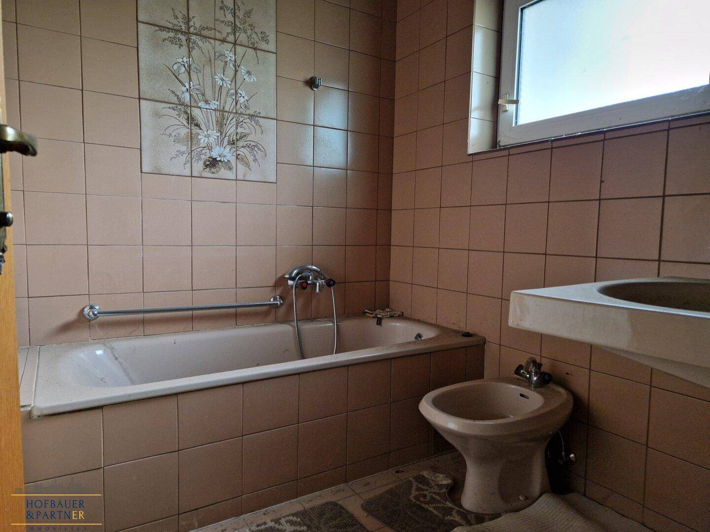 Badezimmer mit Badewanne, Bidet und braunen Fliesen im 80er-Jahre-Stil.