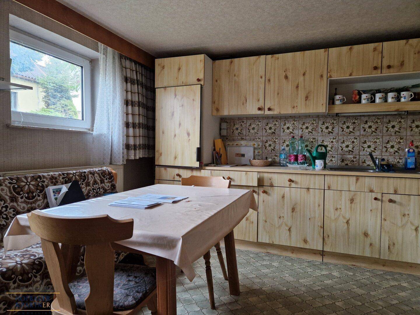 Gemütliche Wohnküche mit Holzküche, Esstisch und gemusterten Fliesen.