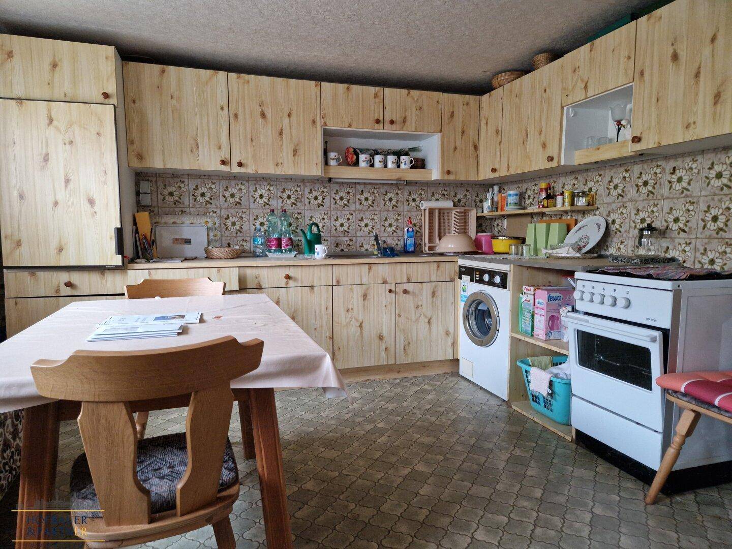 Rustikale Wohnküche mit Holzküche, Esstisch und Waschmaschine.