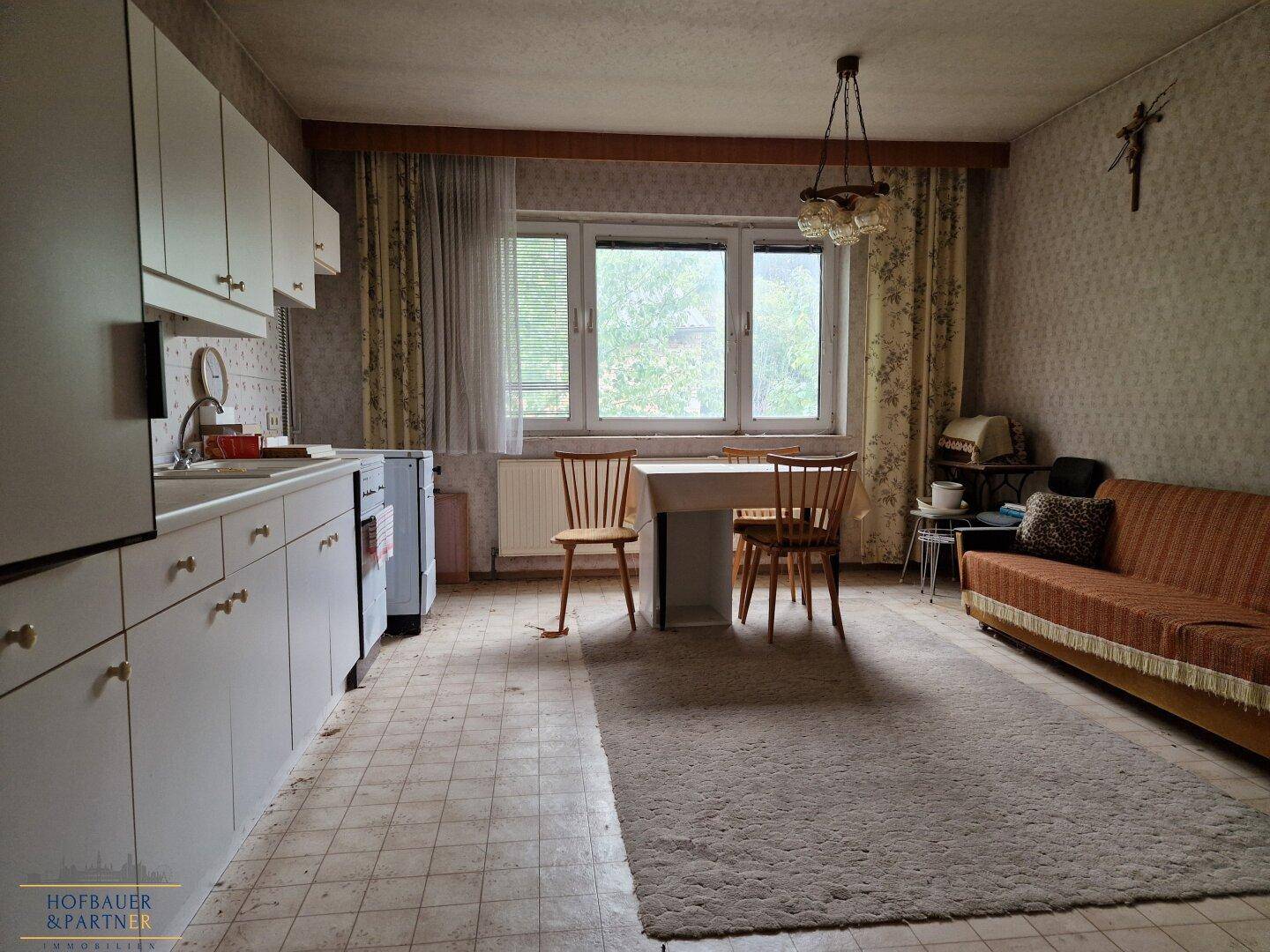 Geräumige Wohnküche mit Esstisch, Sofa und Blick ins Grüne.