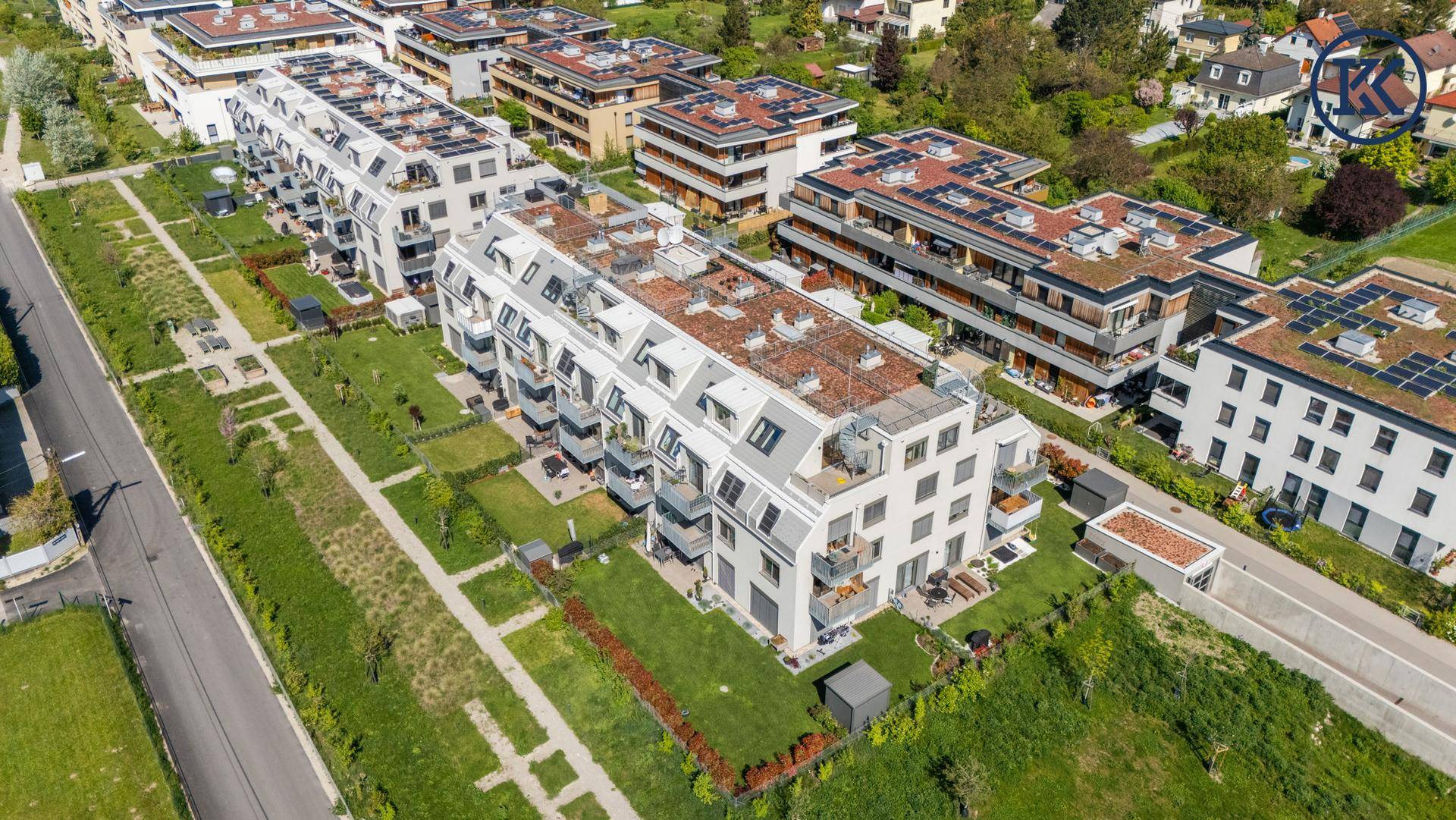 Luftaufnahme einer modernen Wohnanlage mit begrünten Dächern und weitläufigen Grünflächen.