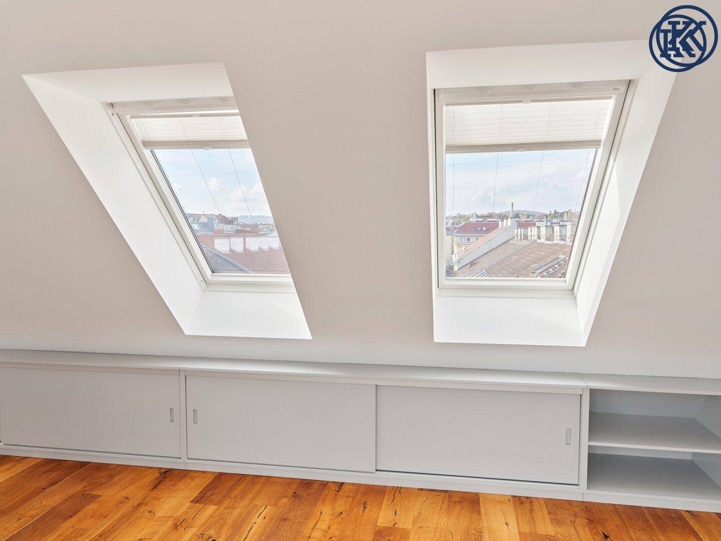 Zwei helle Dachfenster in der Schräge über praktischen Einbauschränken im Dachgeschoss.