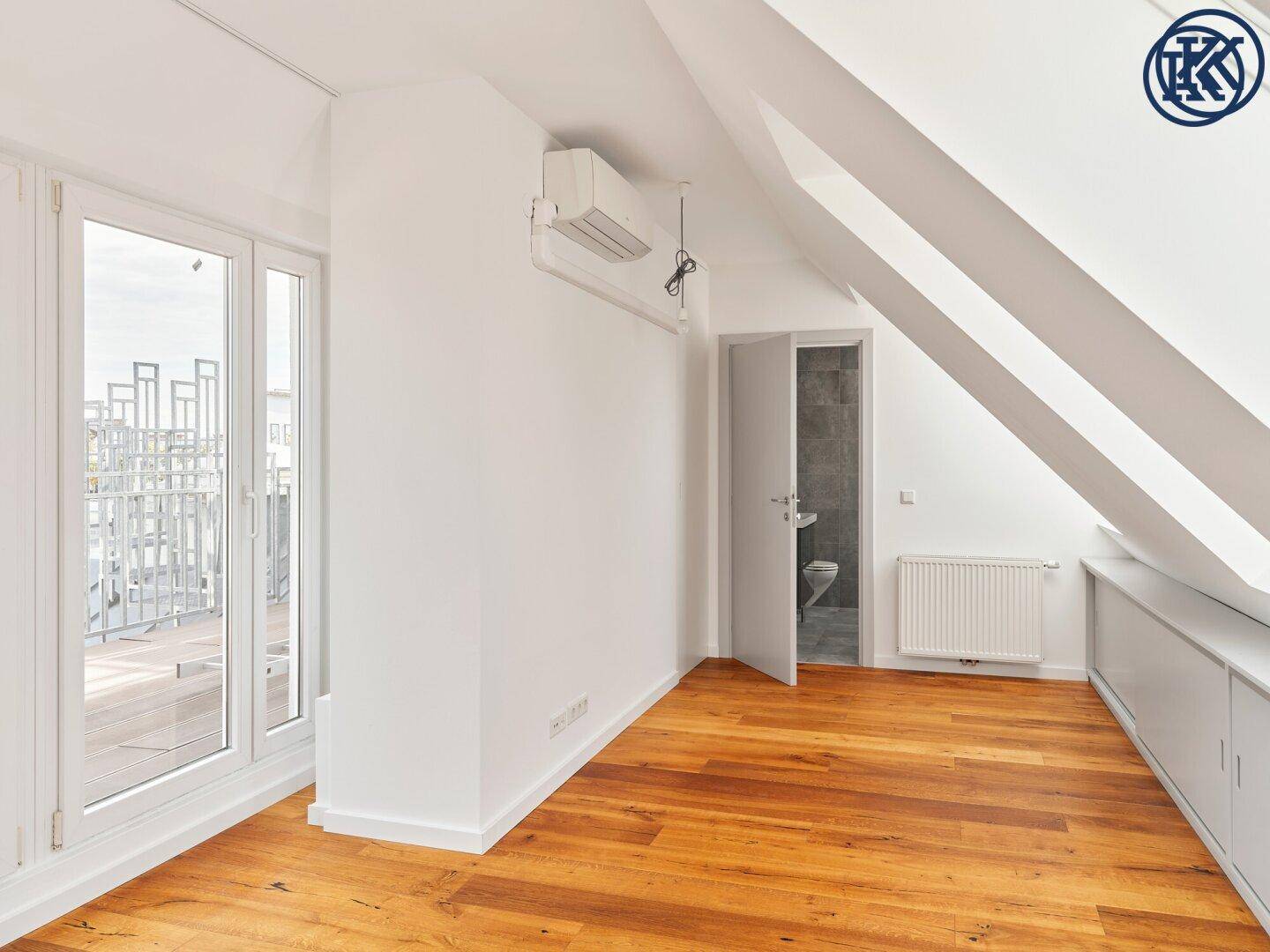 Geräumiges Dachgeschosszimmer mit Holzboden, Einbauschränken und direktem Zugang zur Außenterrasse.