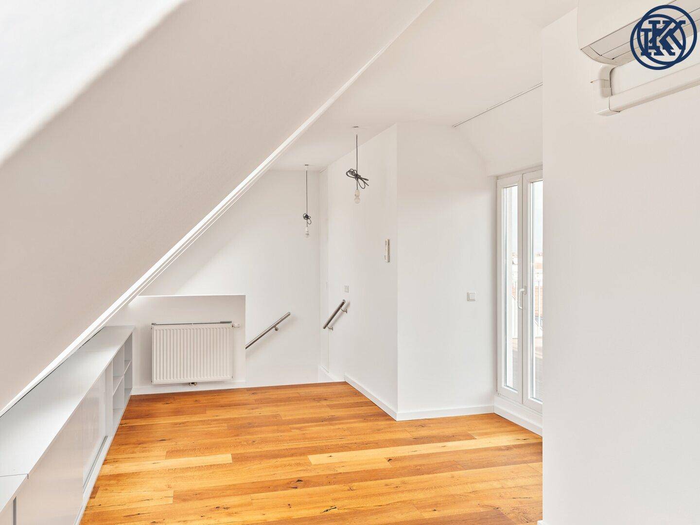 Helles Dachgeschosszimmer mit Holzboden, Dachschrägen und einem Heizkörper, bereit zur Einrichtung.