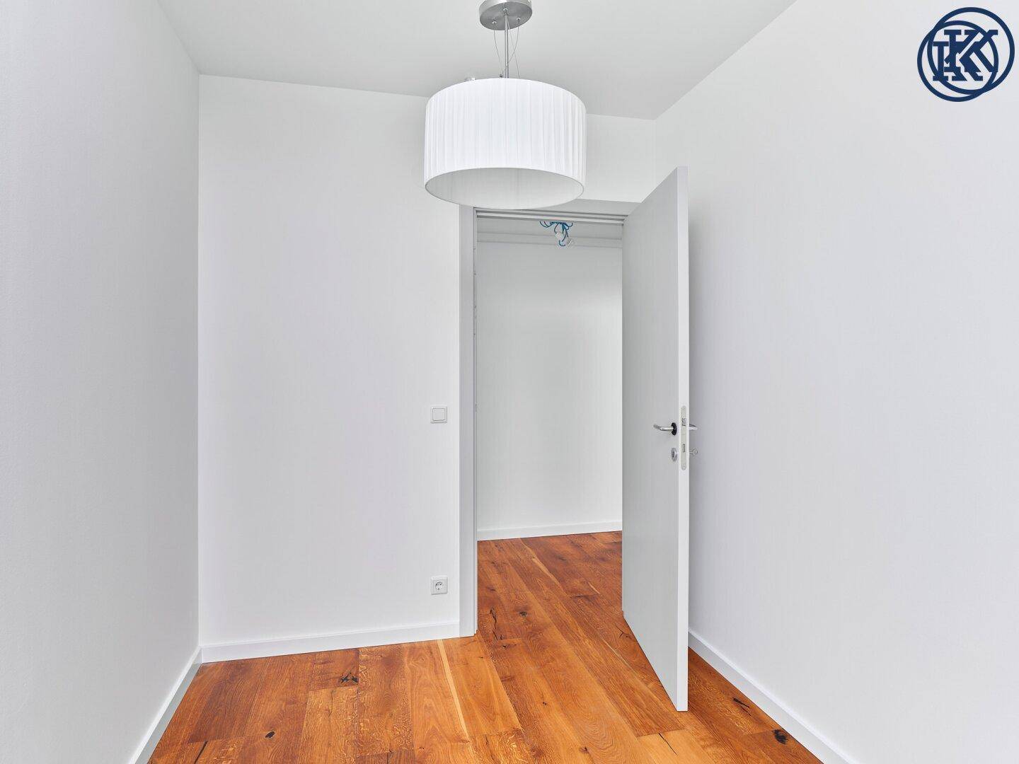 Helles Zimmer mit Holzboden und offenem Zugang zu einem praktischen Abstellraum.