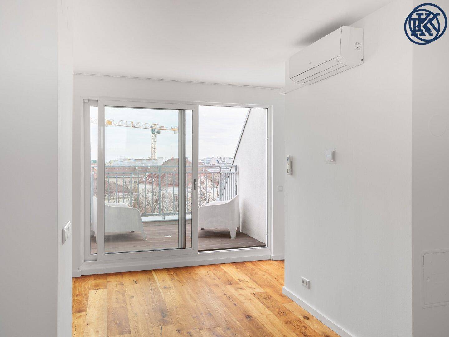Lichtdurchflutetes Wohnzimmer mit Holzboden und großer Schiebetür zum Balkon.