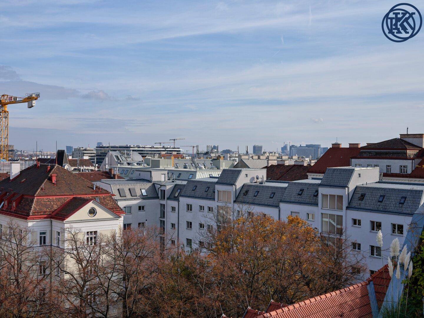 Panoramablick über die städtische Bebauung mit vielen Dächern und Bäumen im Herbstlaub.