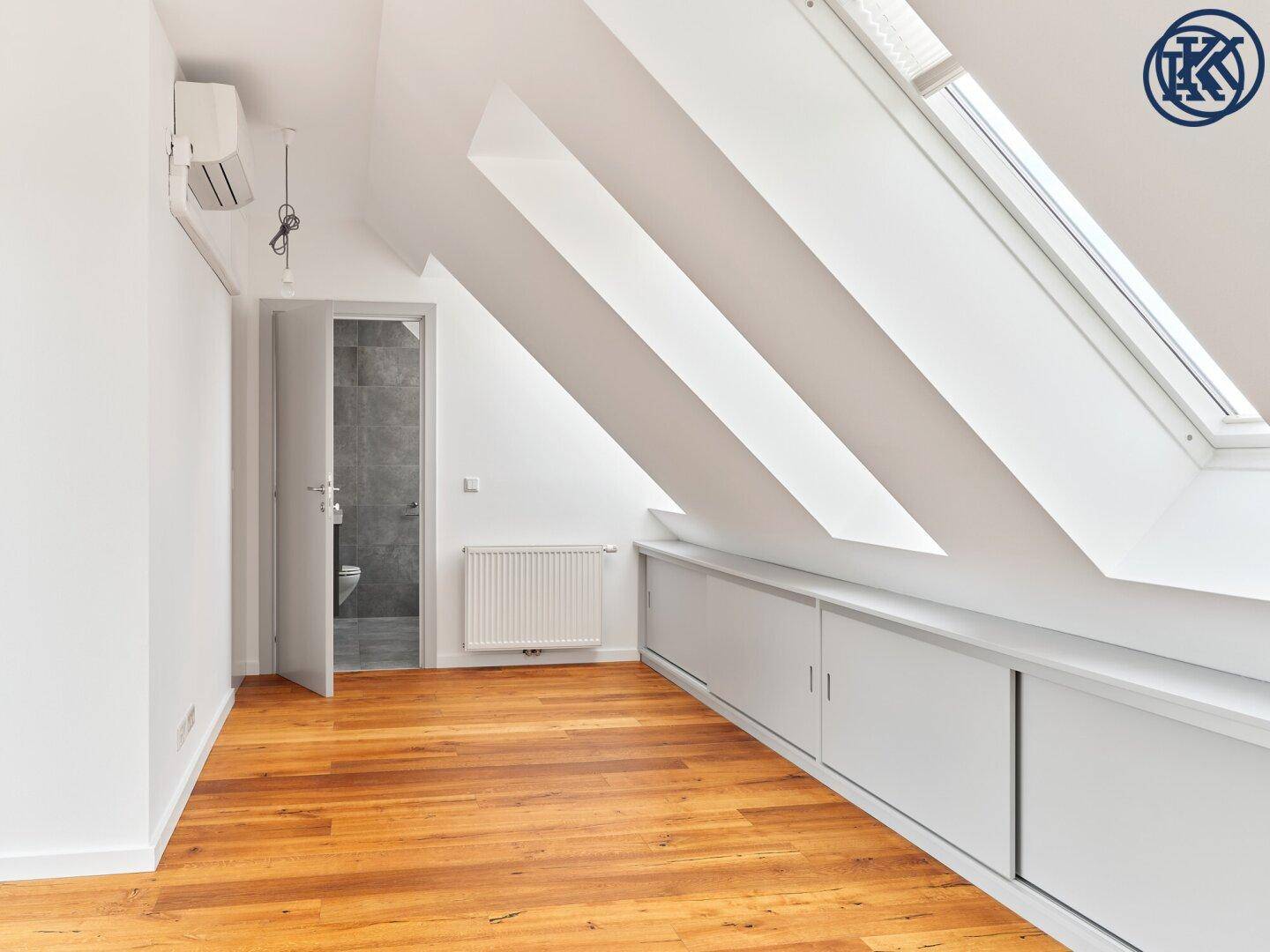 Lichtdurchflutetes Dachgeschosszimmer mit Holzboden, Dachfenstern und praktischen Einbauschränken.