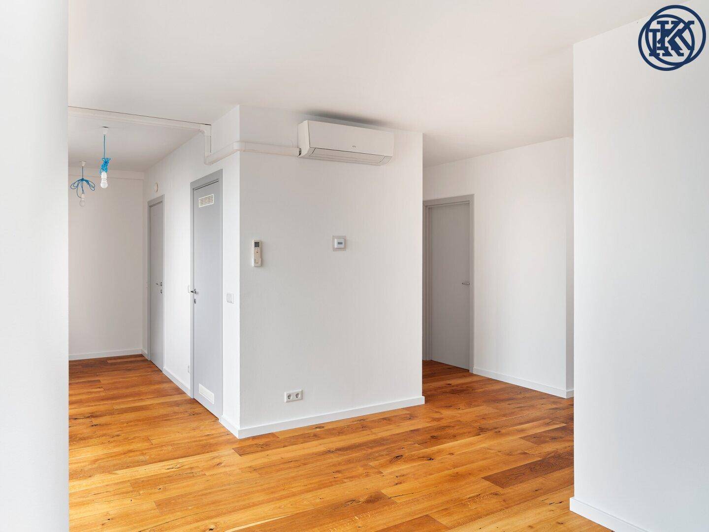 Helles Zimmer mit Holzboden und Klimaanlage, das als Wohnbereich oder Flur dienen könnte.